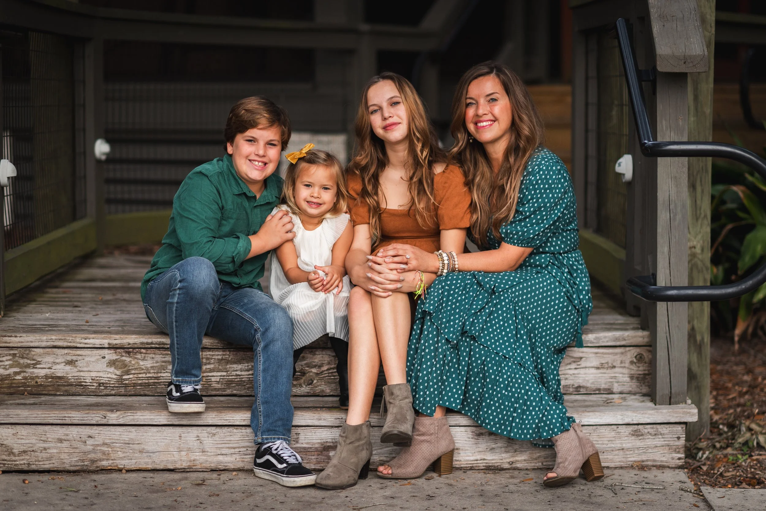 Mother with three kids smiling on porch steps, FishHawk