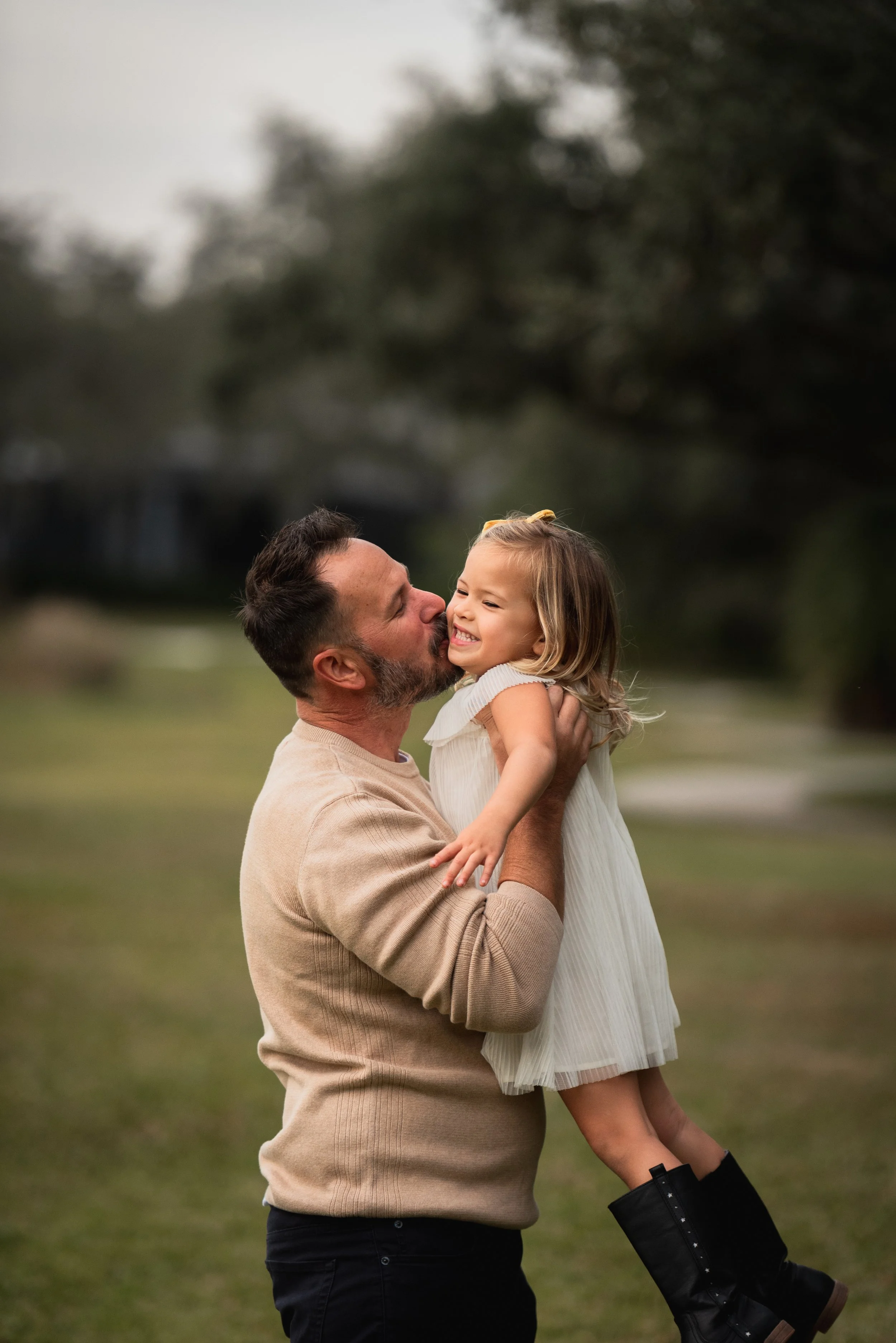 Father kissing his young daughter's cheek outdoors