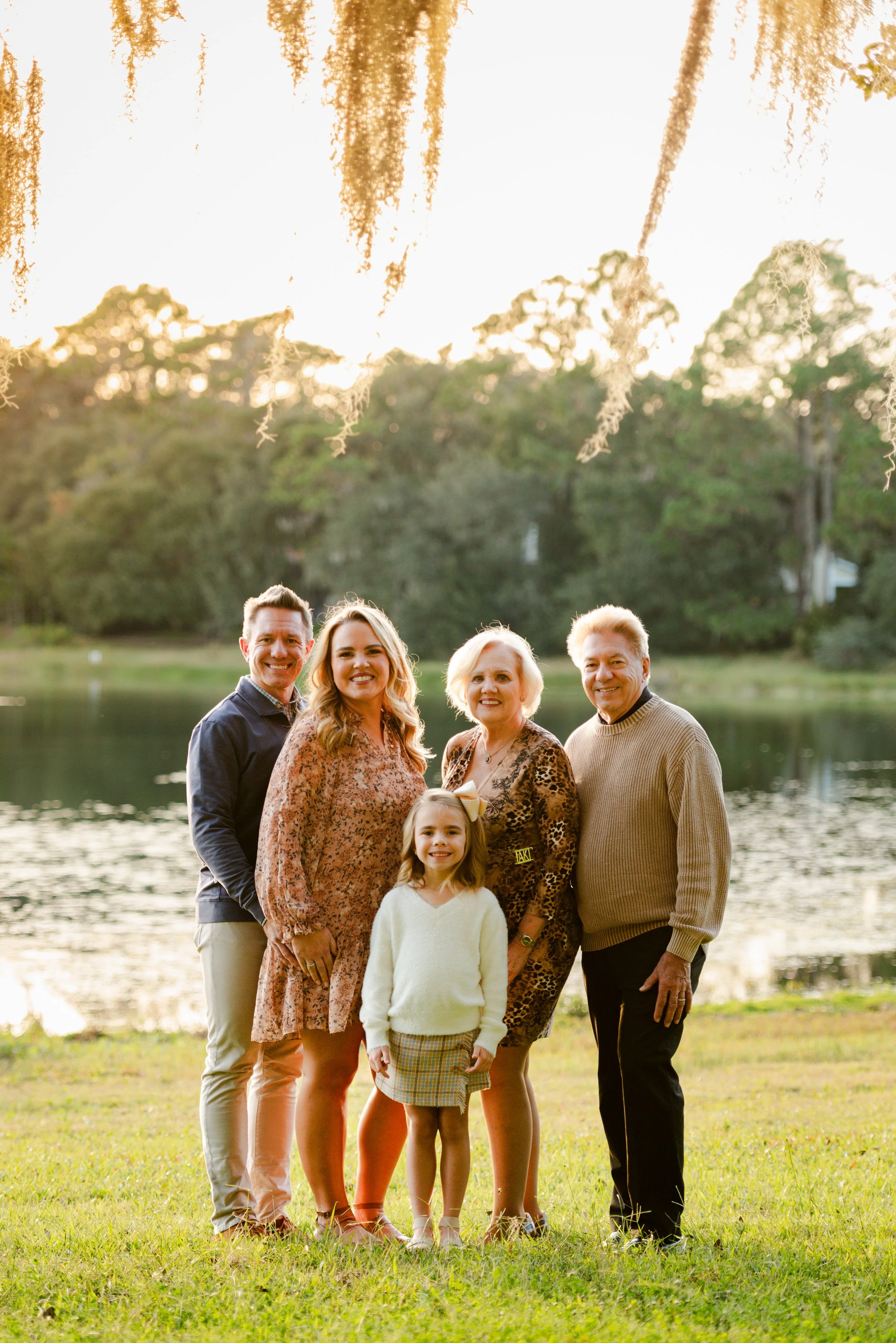 Three-generation family portrait by the lake with Spanish moss overhead