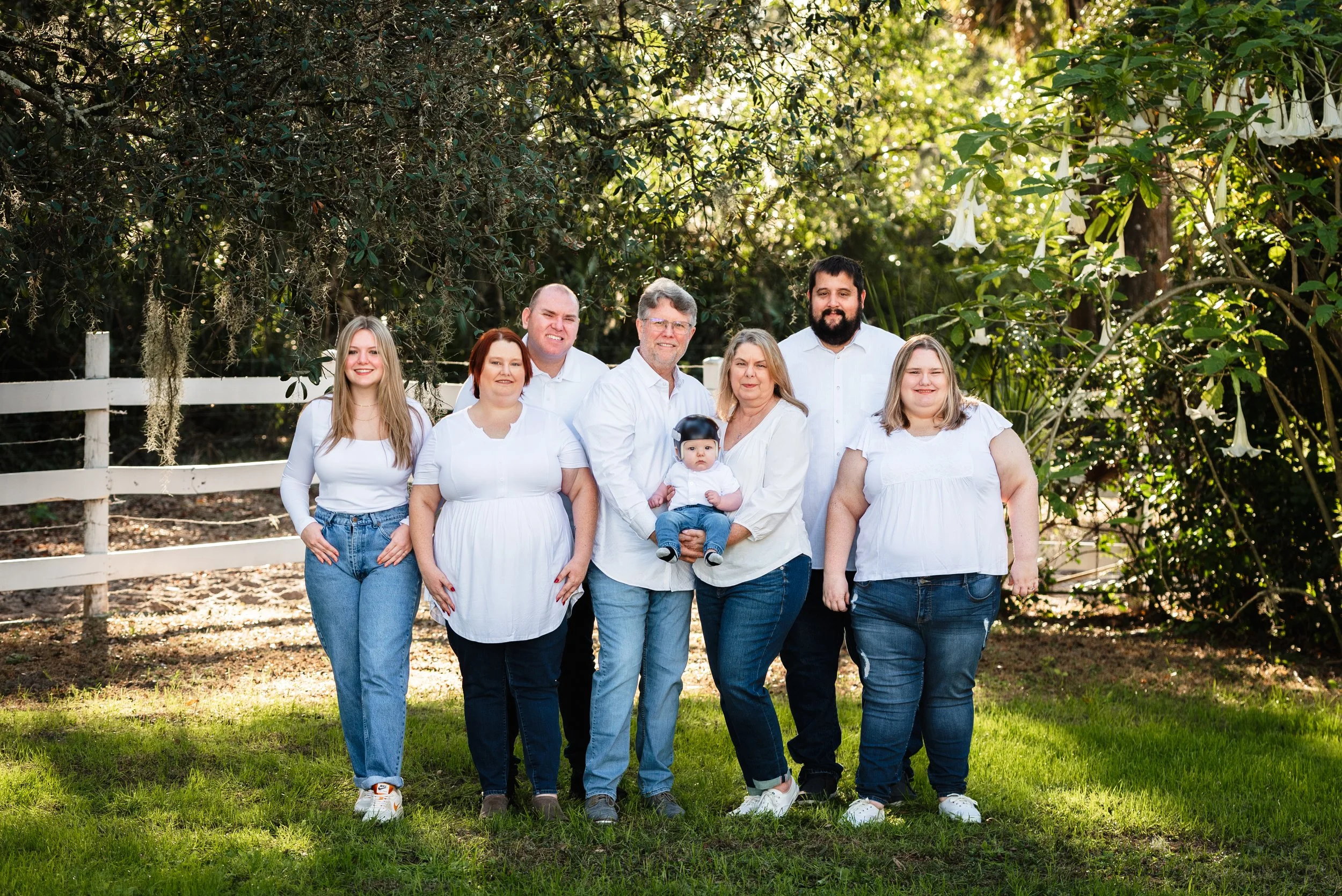 Extended family standing together near white fence, Lithia Acres