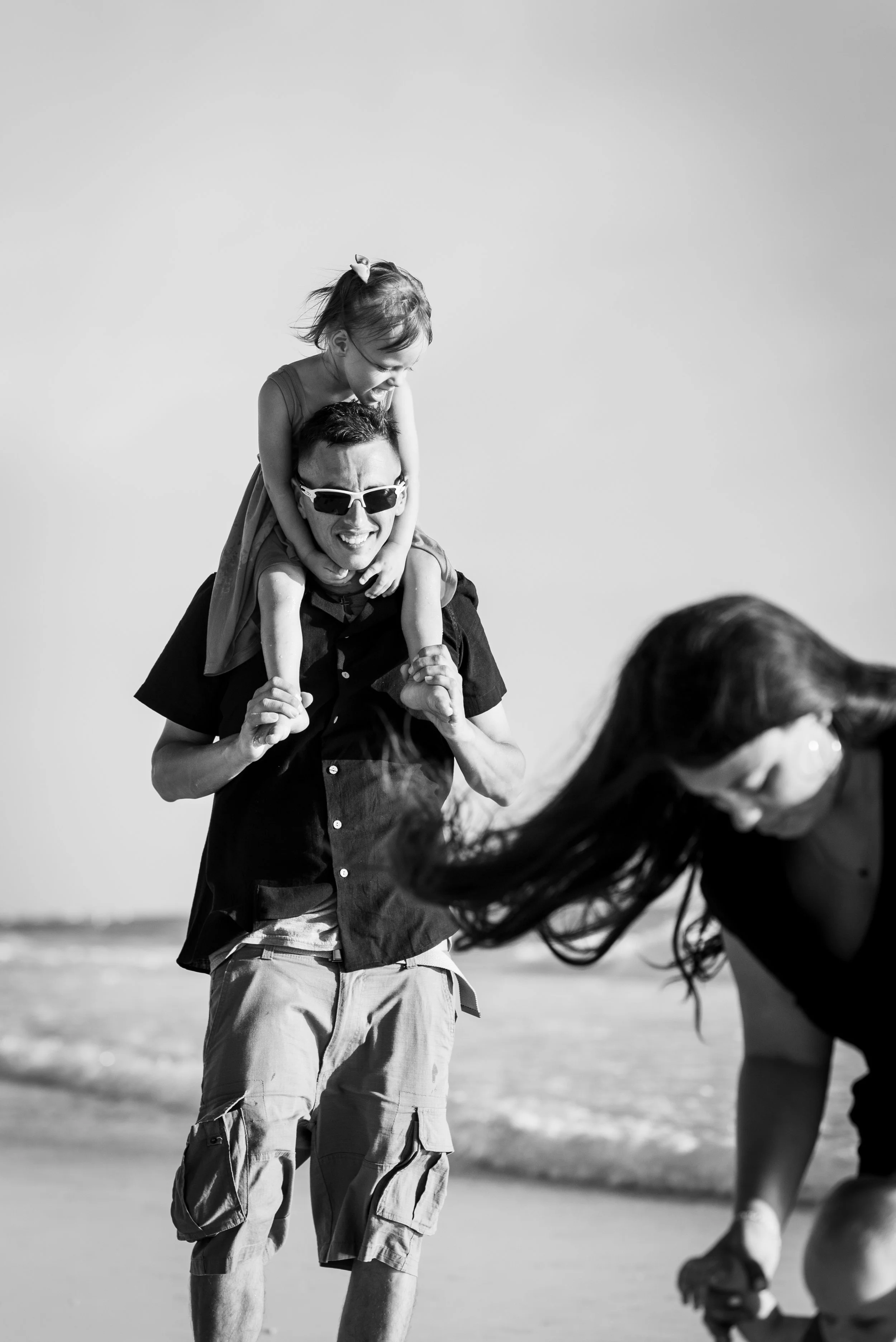 Black and white photo of father carrying daughter on shoulders, Coquina Beach