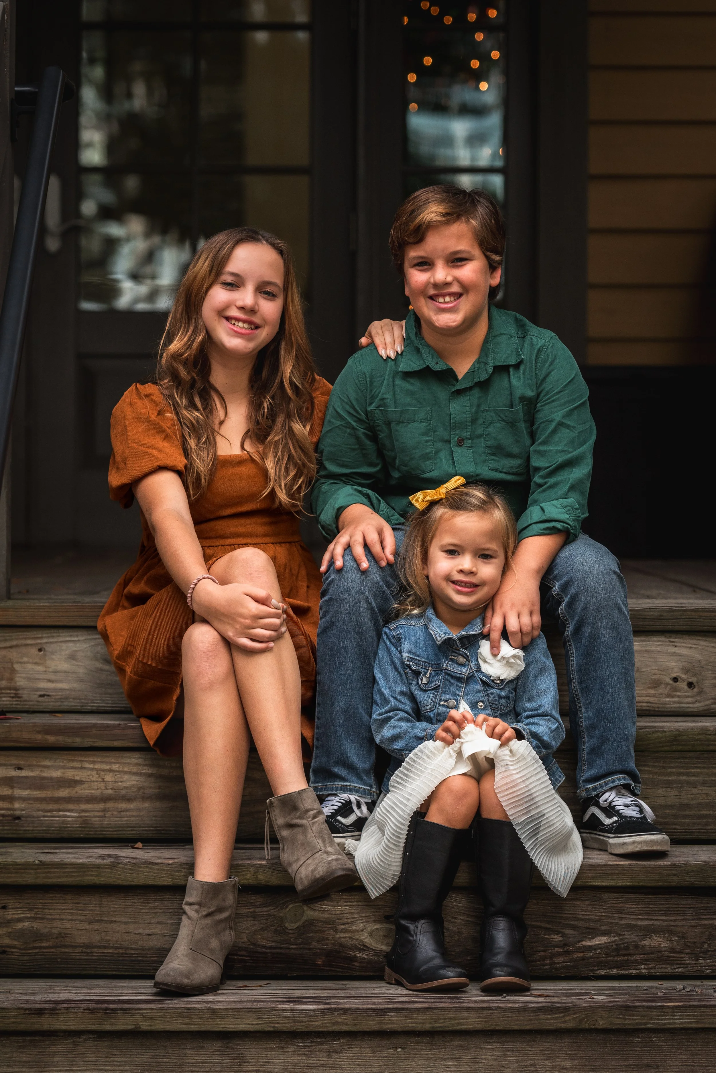 Two siblings and a toddler sitting together on porch steps