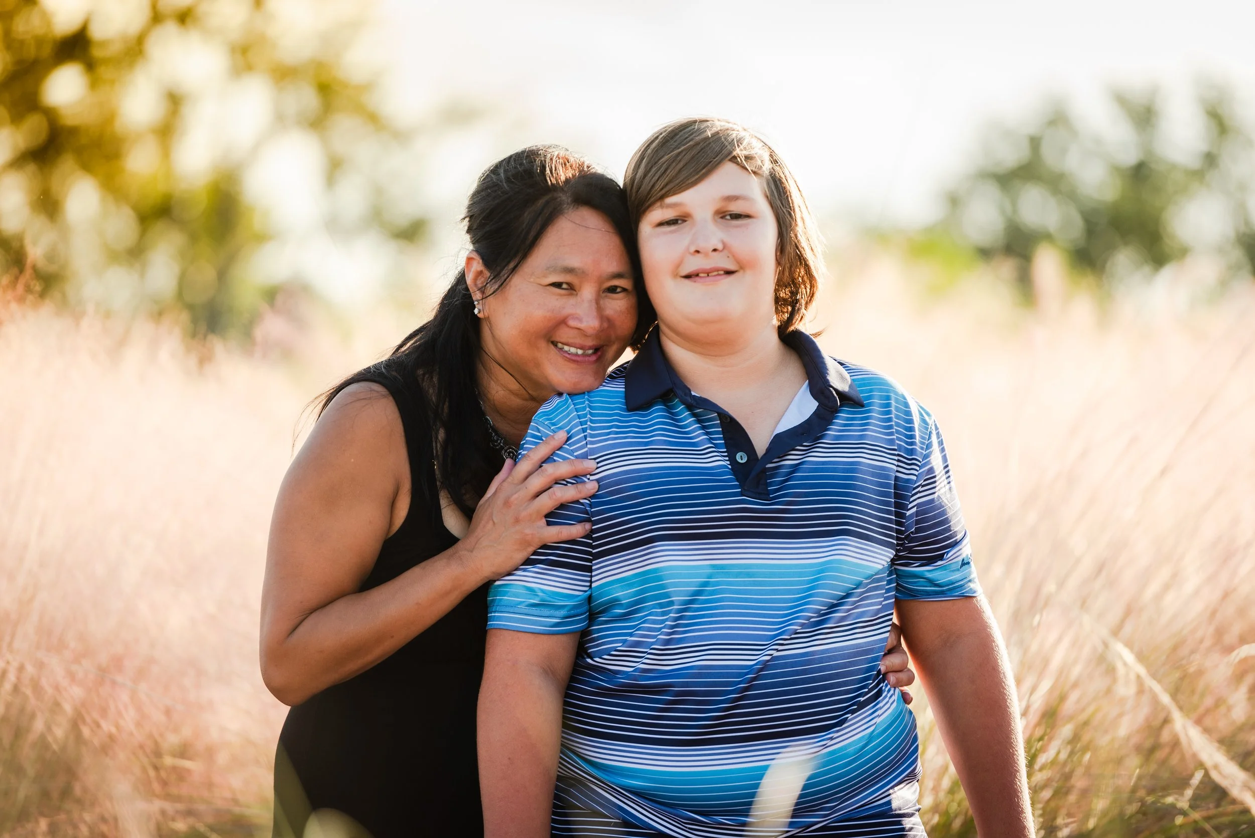 Mother and son portrait in a field of golden grass at sunset