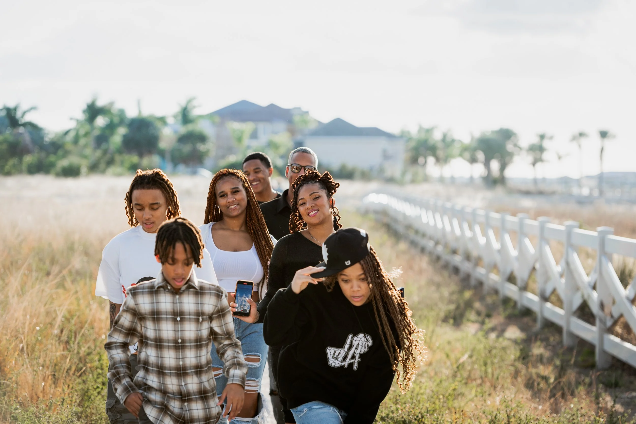 Family walking together along a grassy path with a white split-rail fence at Apollo Beach Nature Preserve