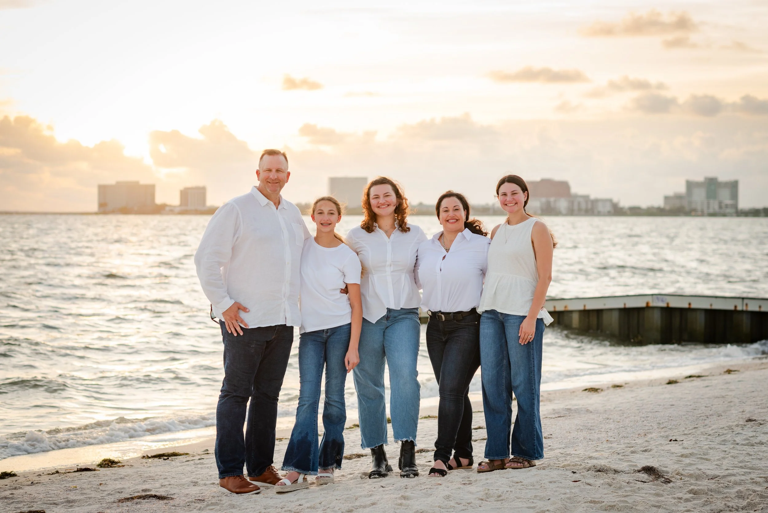 Family standing on beach at sunset with Tampa skyline, Cypress Point Park