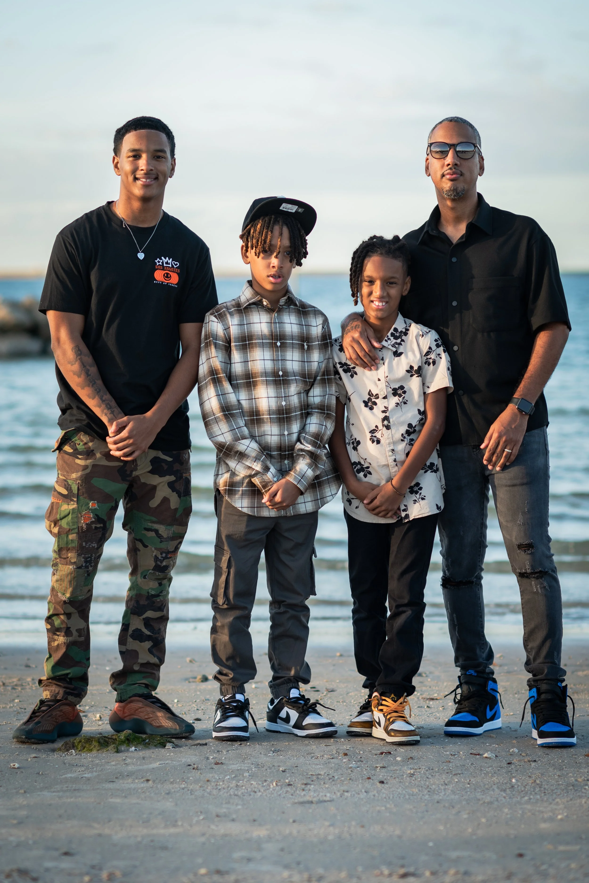 Father and three sons standing together on the beach at Apollo Beach Nature Preserve at sunset