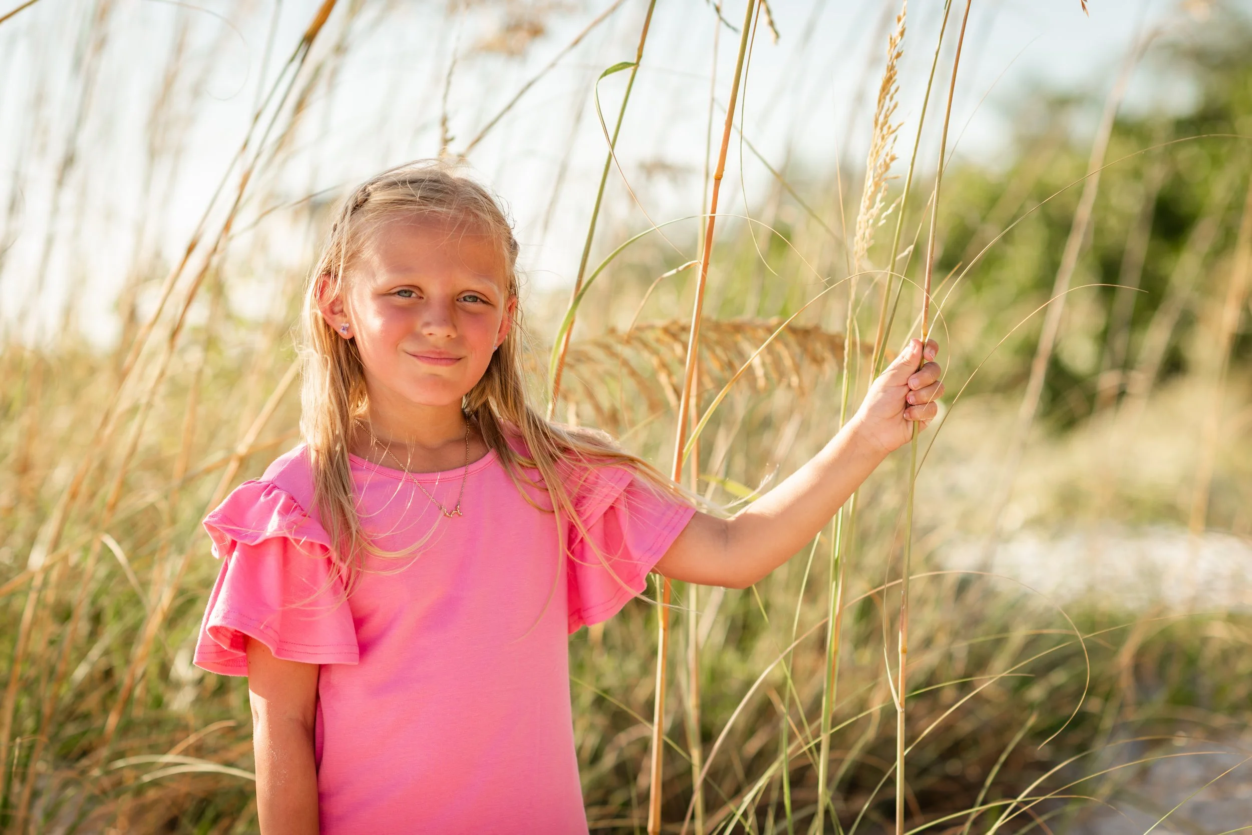 Young girl in pink dress standing in sea oats at Coquina Beach