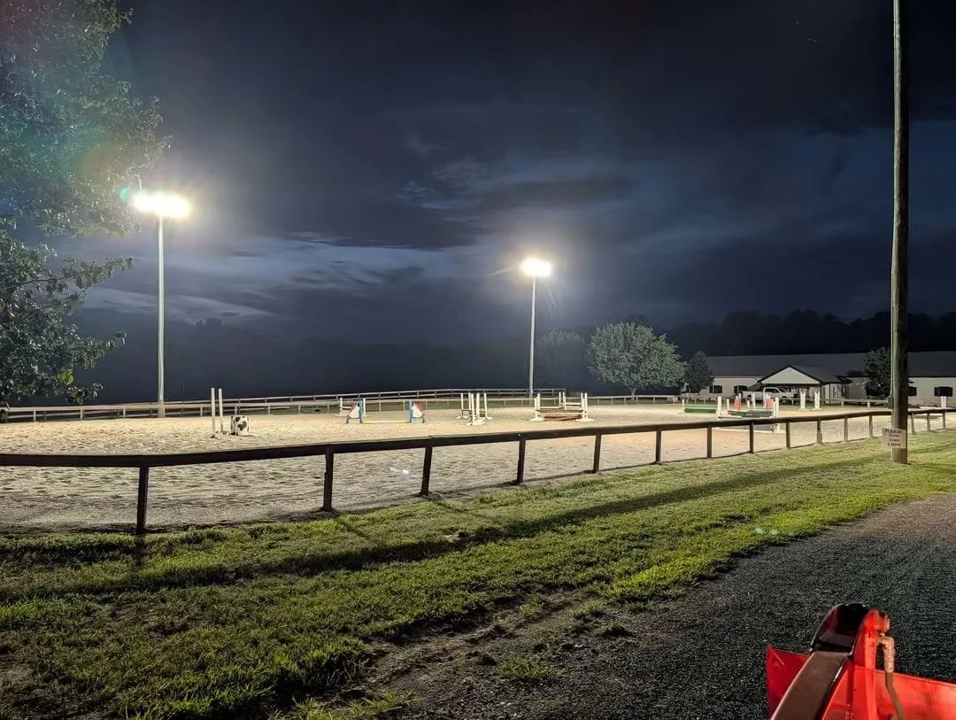 Outdoor night scene of well lit riding arena.