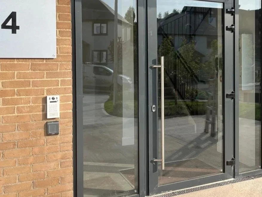 Glass door with metal handle, brick wall with house number 4, intercom, and doorbell
