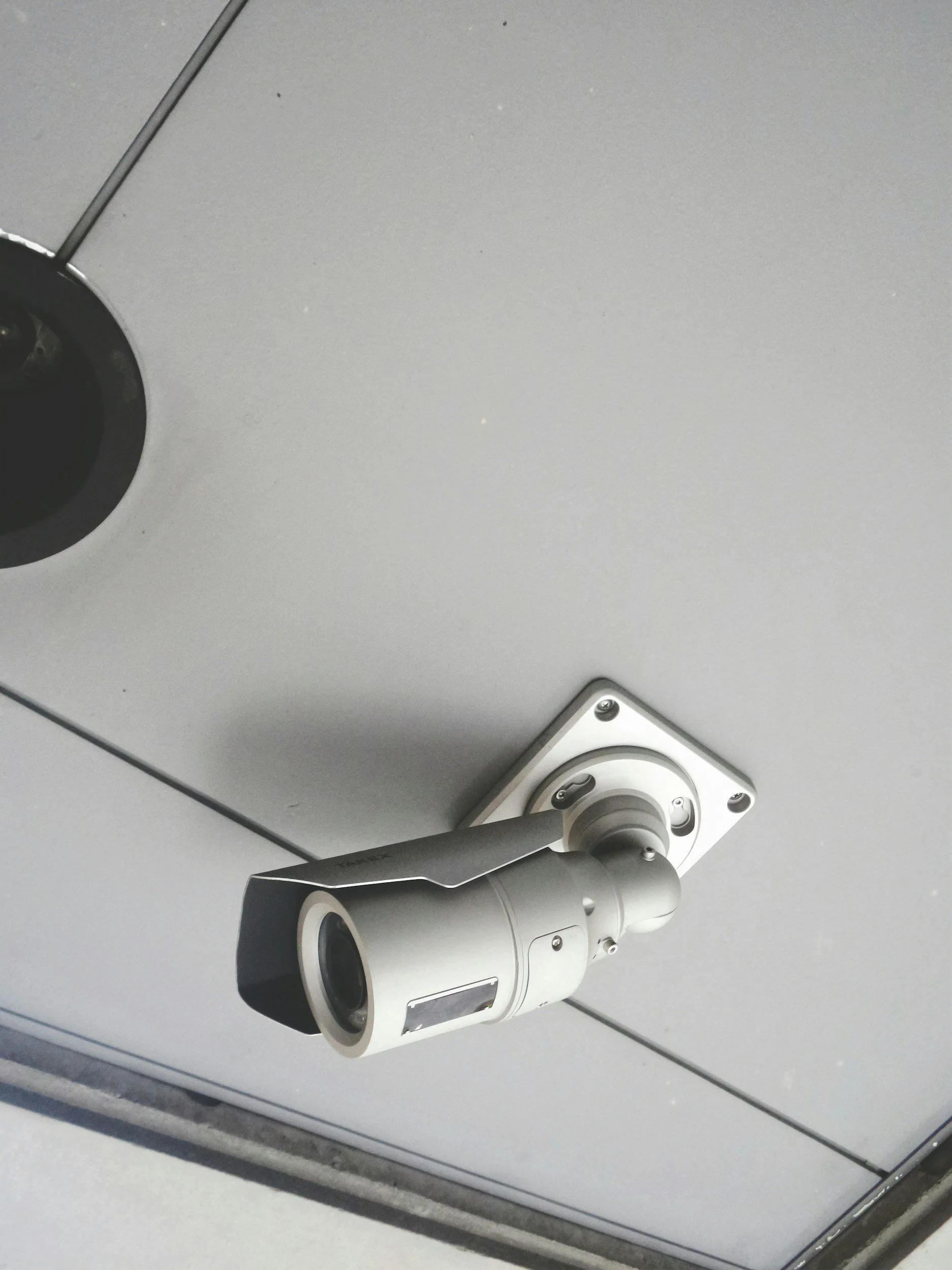 Security camera mounted on a ceiling or wall in a modern interior setting.