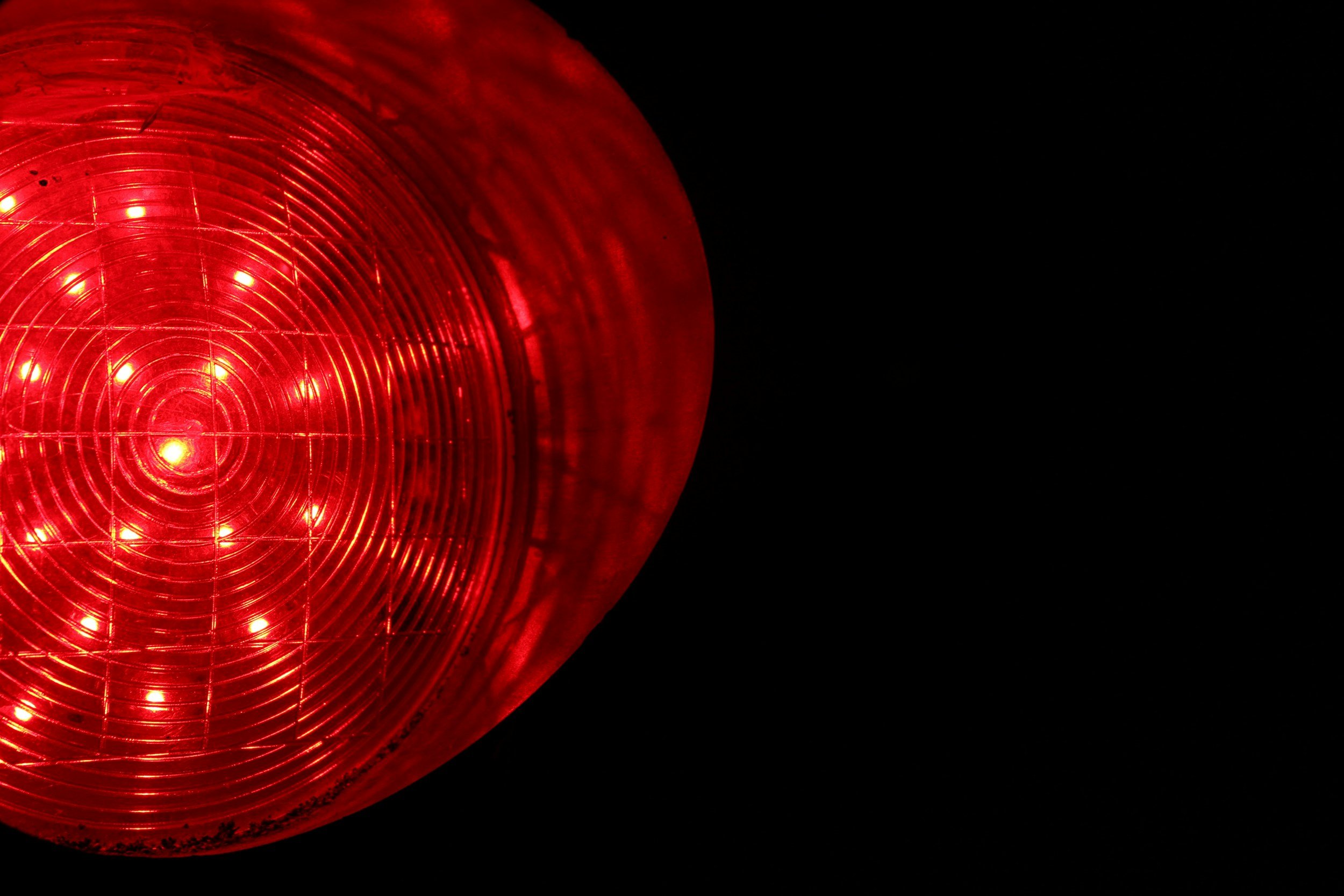 Close-up of a red illuminated circular reflector or light against a black background.