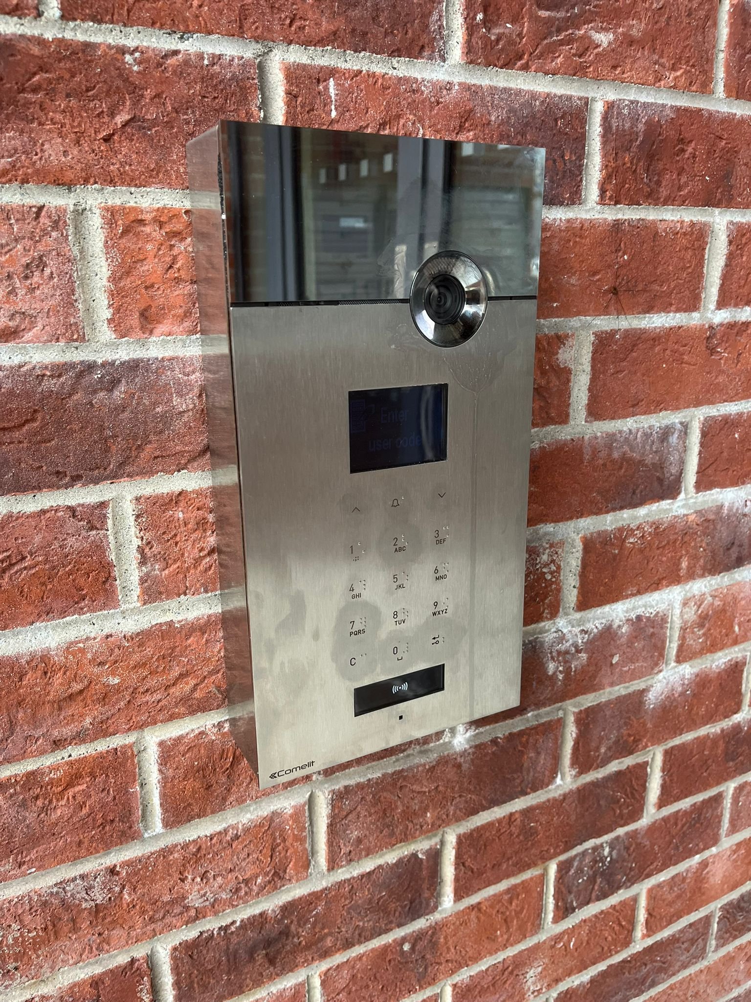 Intercom system with camera mounted on a brick wall.