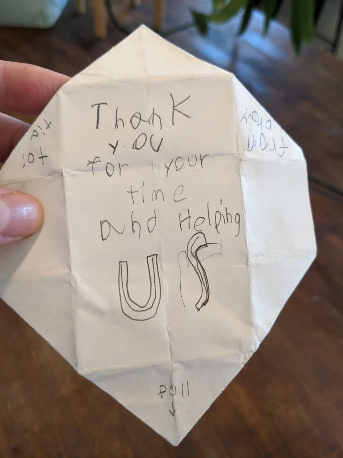 A handwritten thank you note on a crumpled piece of paper with the words 'Thank you for your time and helping us' and a large drawn 'US' in the center.