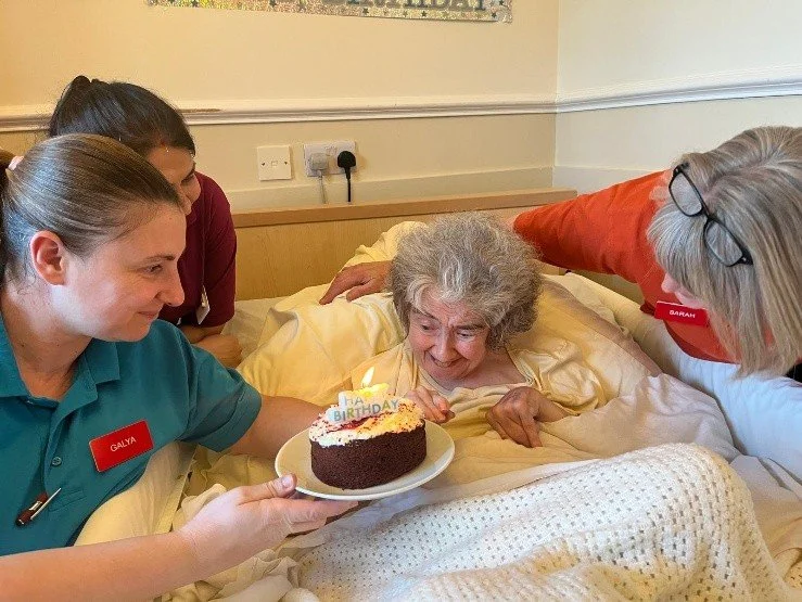 Lilian Faithful care home resident with carers and birthday cake