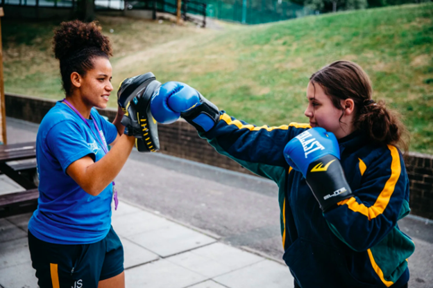 two young people practicing boxing together outside