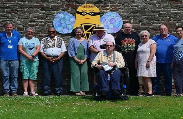 group of people outside in front of a stone wall