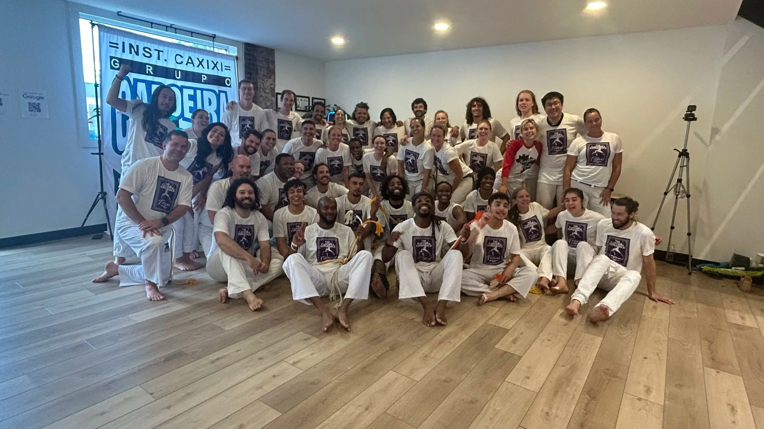 Group of people dressed in white martial arts uniforms, posing together for a photo indoors.