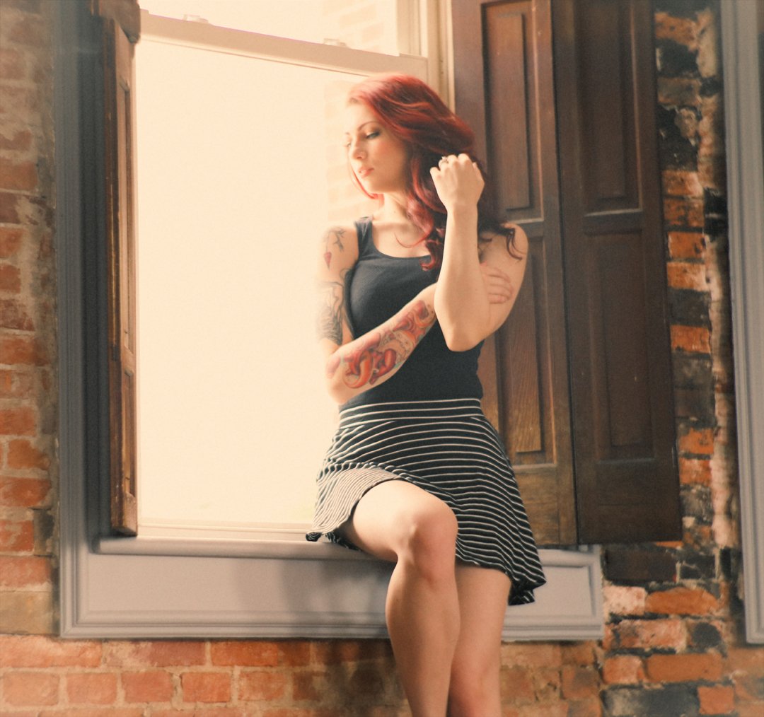 Photo of a woman sitting on a window sill.