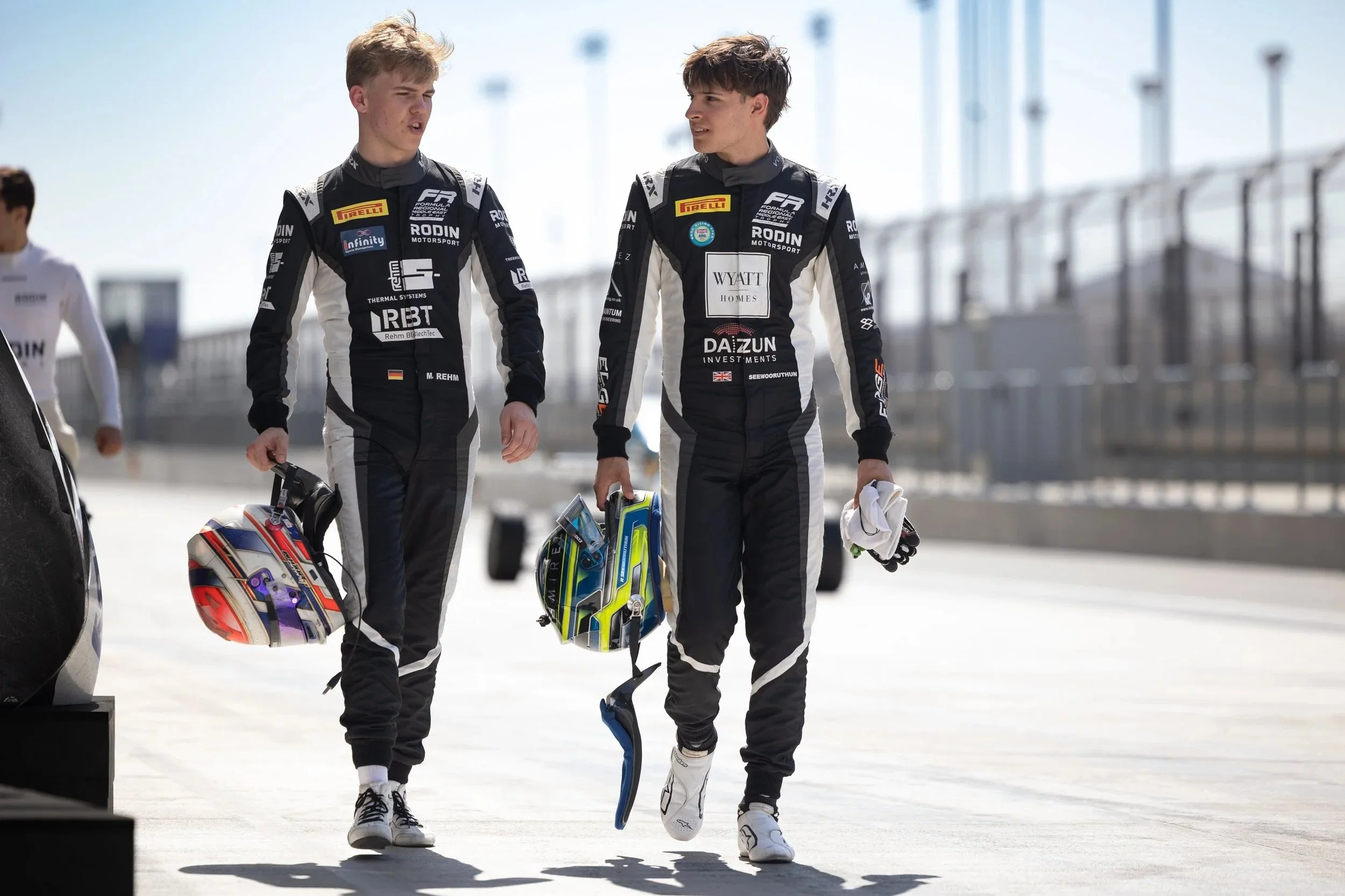 Reza Seewooruthun and Maxim Rehm walking down the pit lane at Lusail International Circuit in their Rodin Motorsport suits