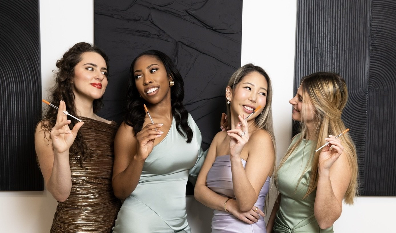 Group of six women smiling in a studio setting