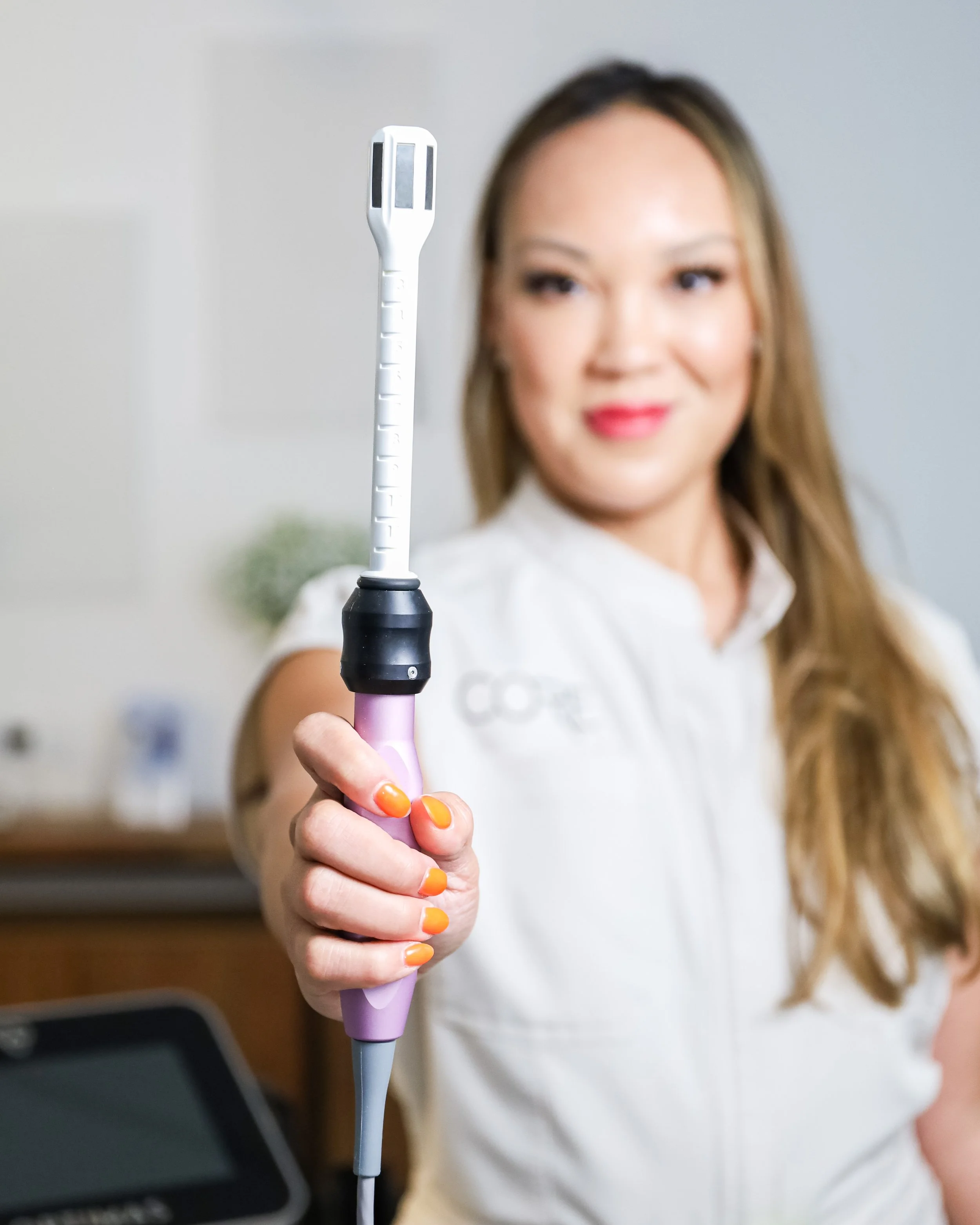Woman holding a medical device in a clinic setting.