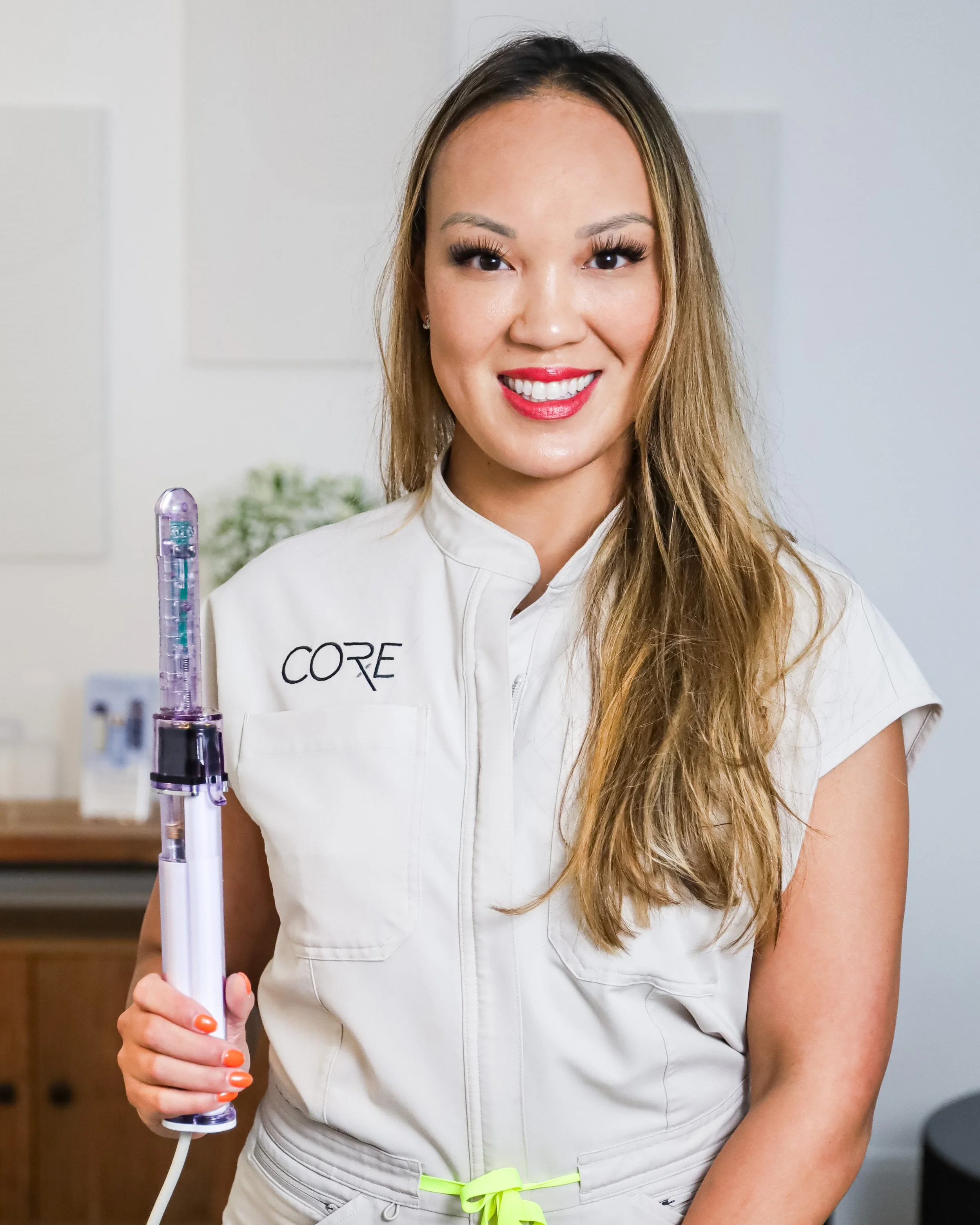 Smiling woman in uniform holding a medical device in a professional setting.