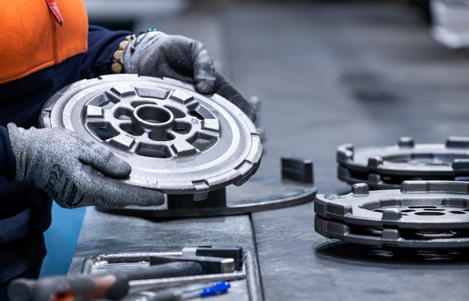 Manos comprobando una pieza metálica durante el control de calidad, gesto de verificación y criterio.