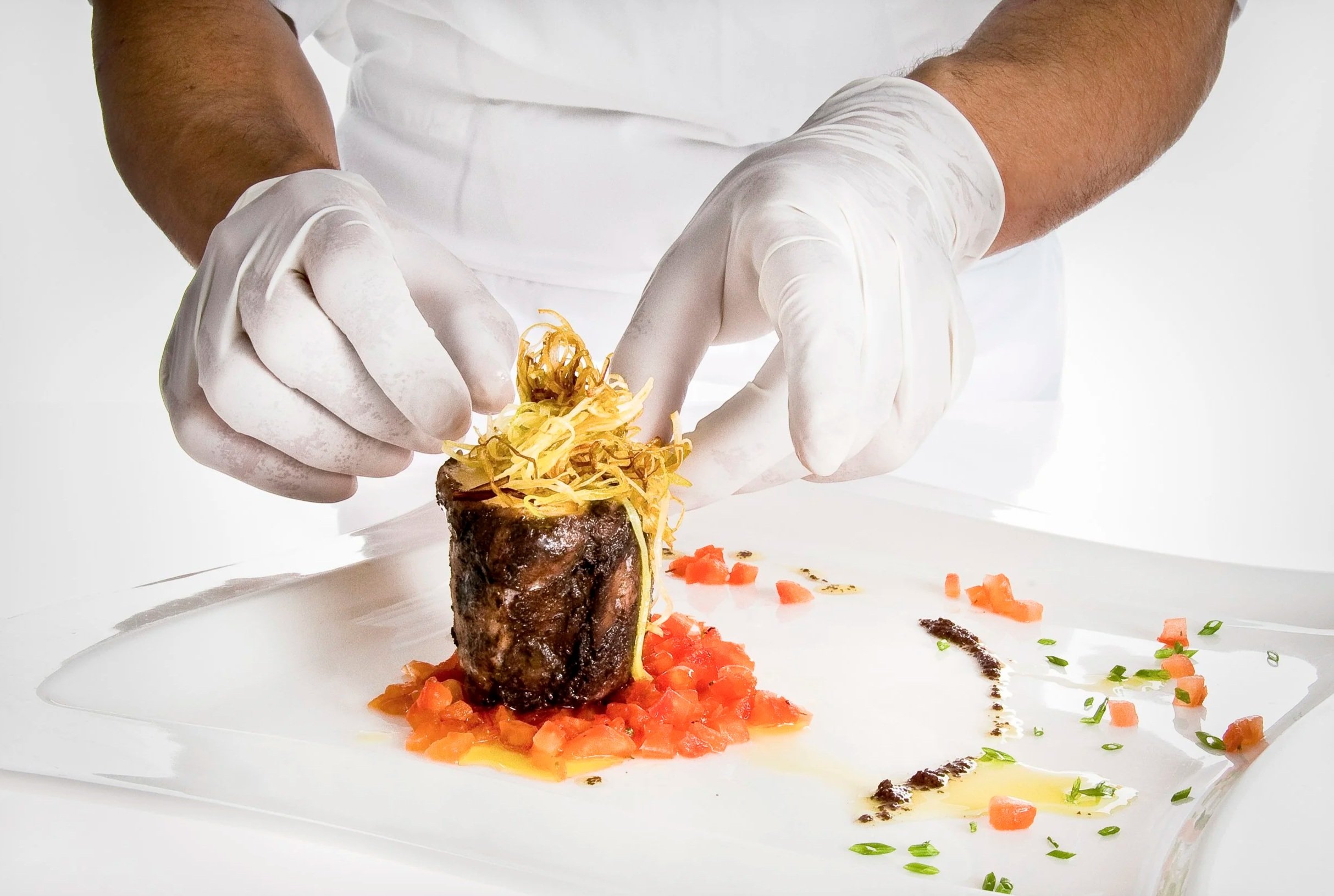 Detalle de manos durante el emplatado en el restaurante del Hotel César (Vilanova i la Geltrú), fotografía de proceso culinario.