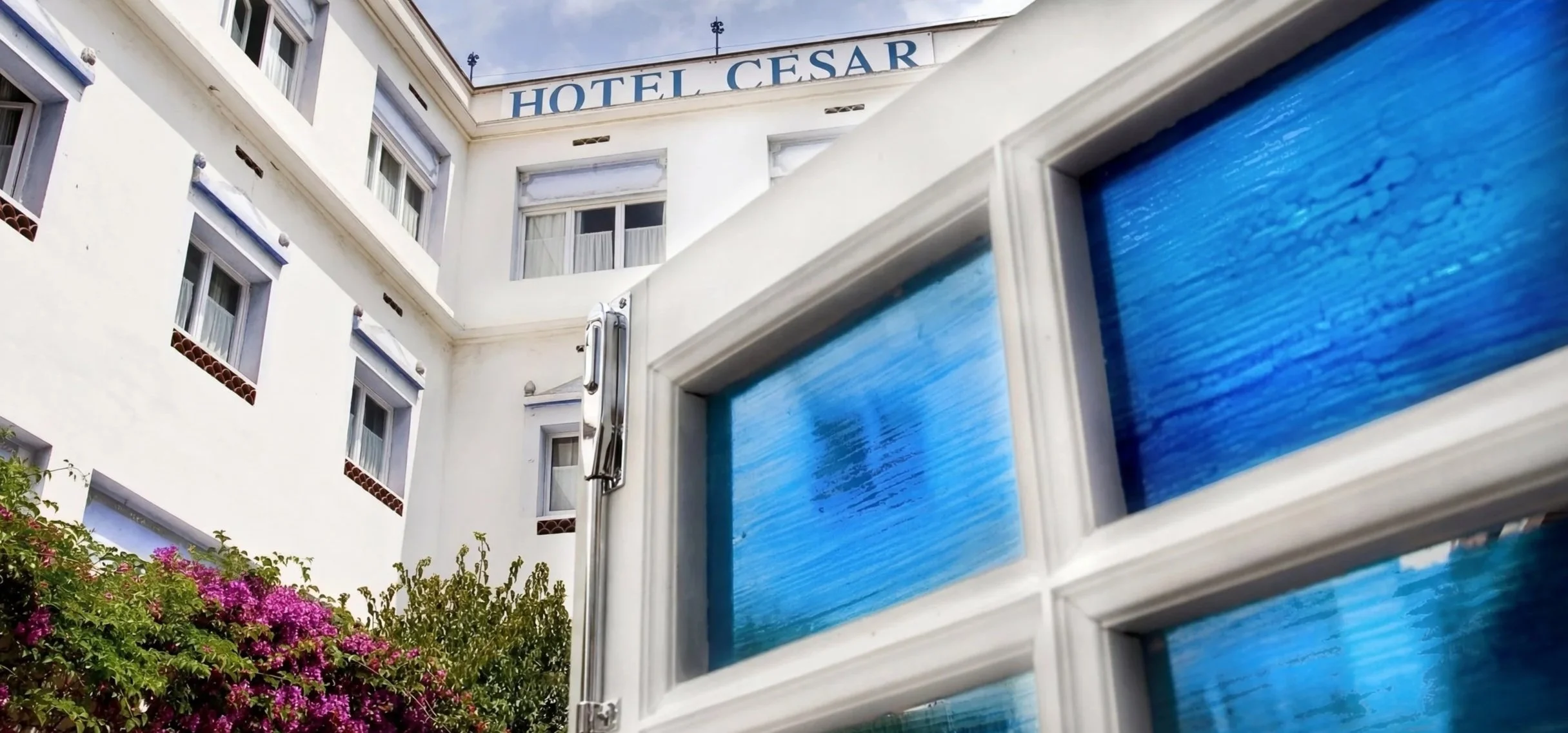 Fachada del hotel y rótulo, con las vidrieras azules como identidad.