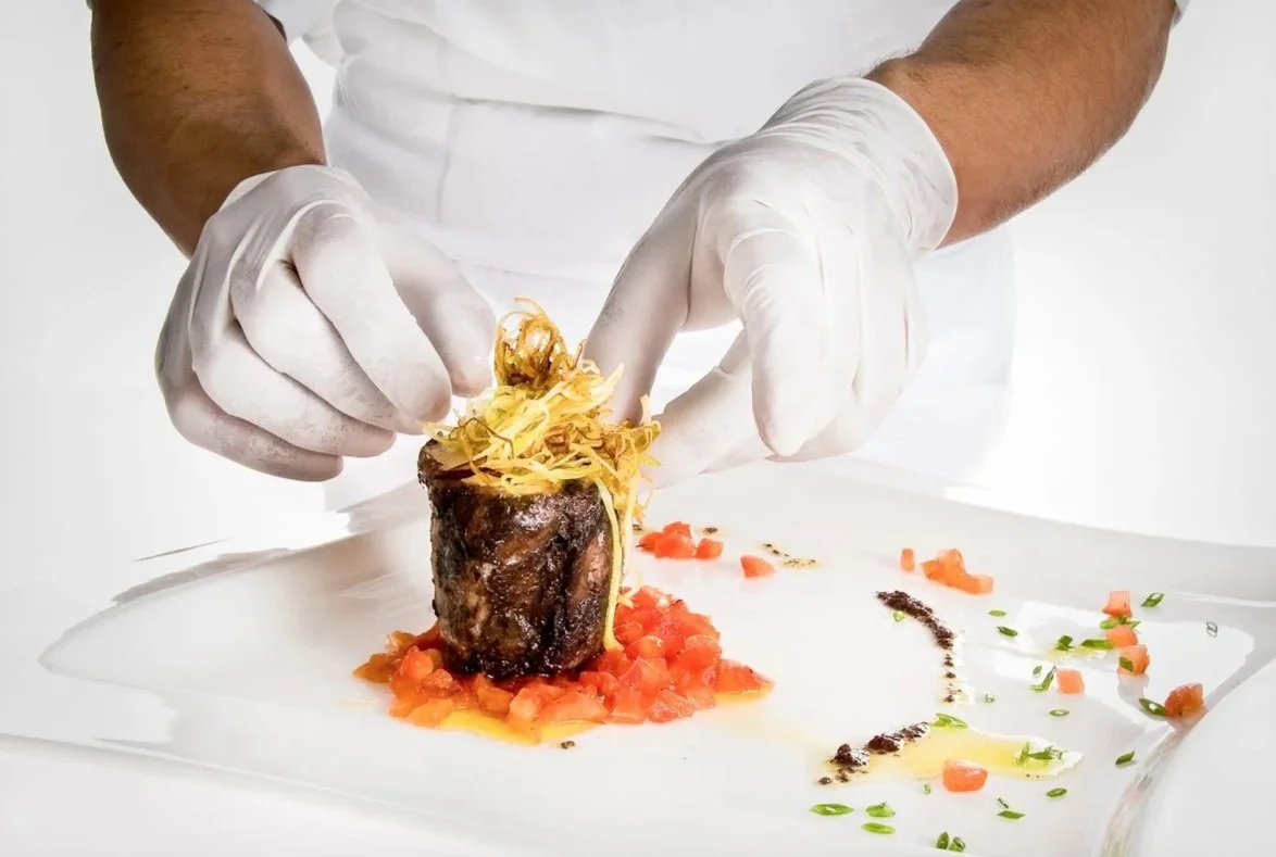 Manos del chef emplatando — cocina en acción (hotel y restaurante)