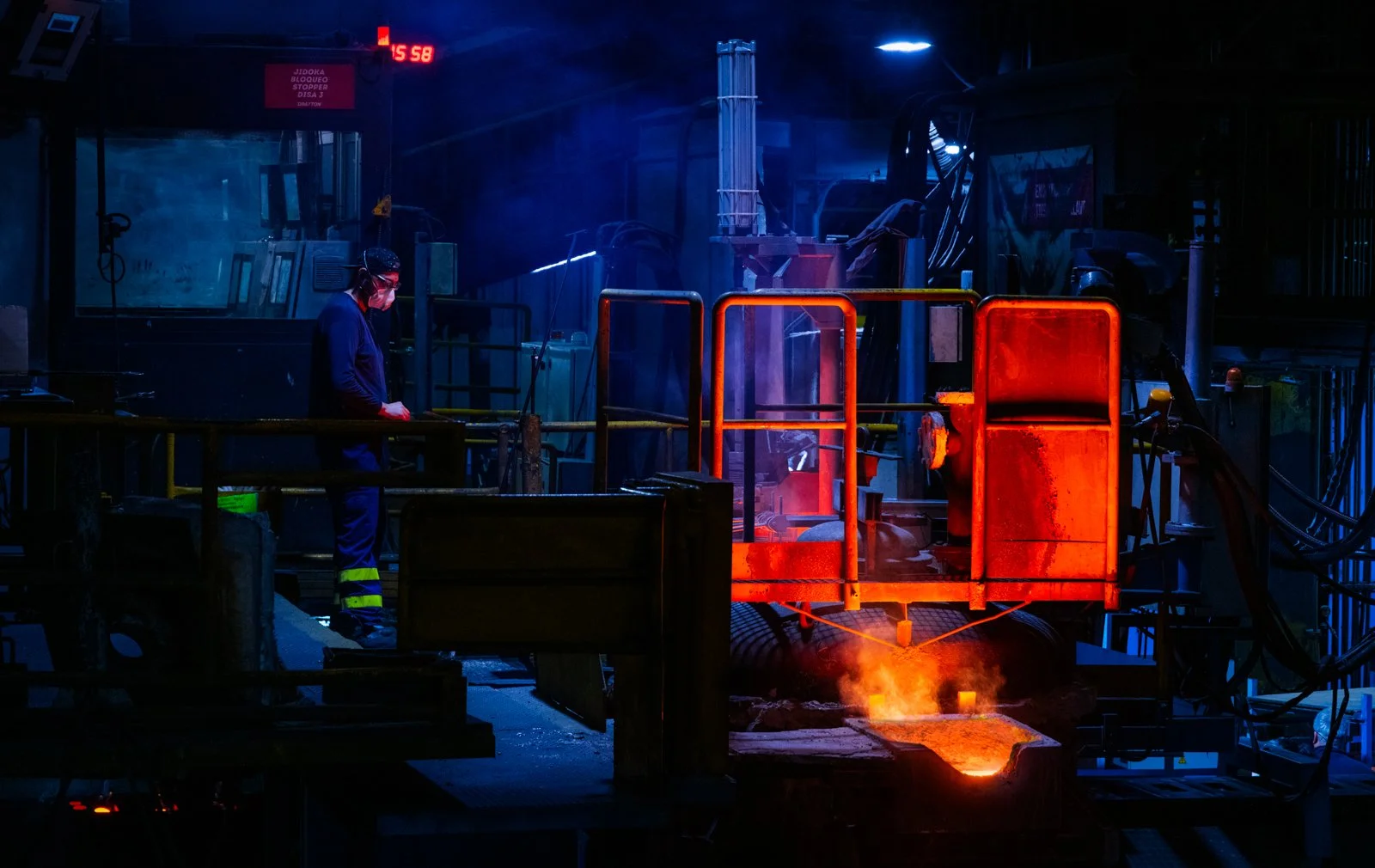 Escena de fundición industrial con metal caliente y maquinaria, atmósfera de calor y proceso en planta.