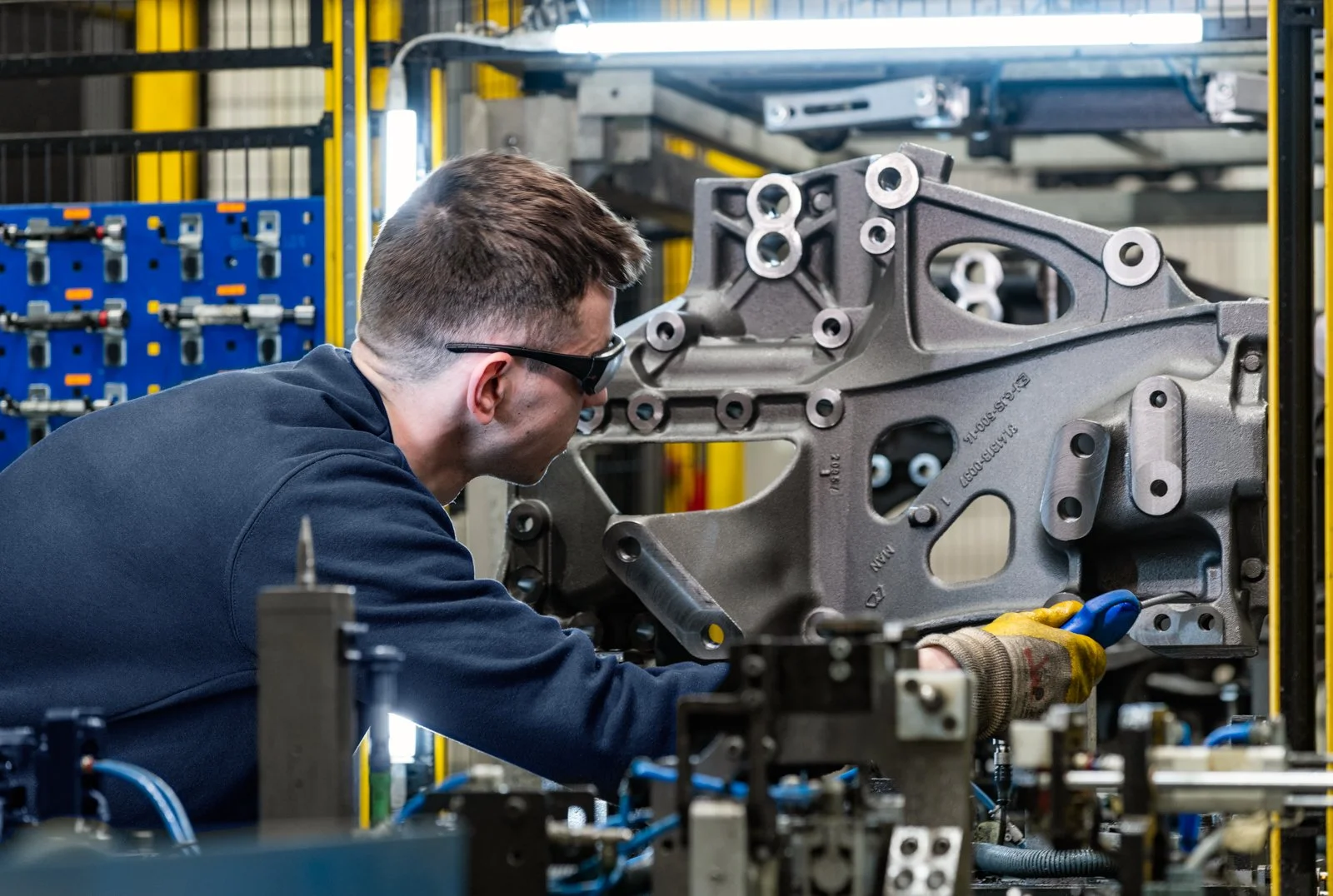 Persona trabajando junto a maquinaria automatizada en un entorno industrial, tecnología y criterio en acción.