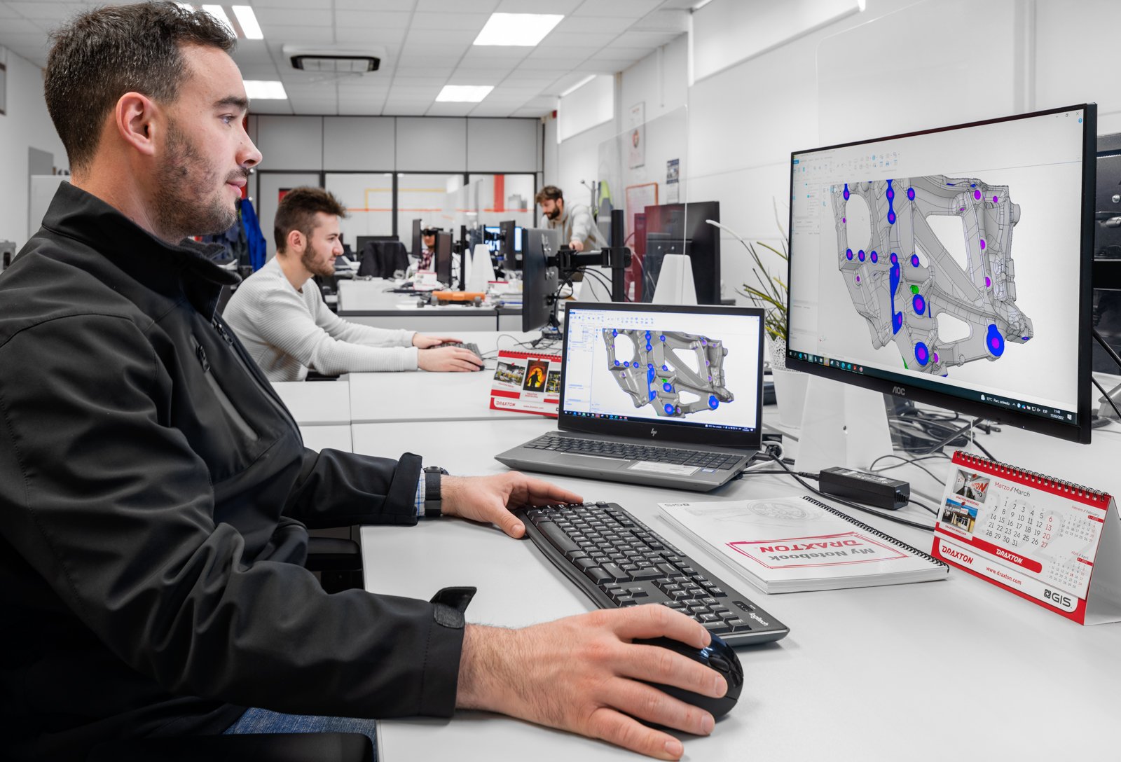 Departamento de diseño de Draxton con un técnico en primer plano y puestos de trabajo al fondo.