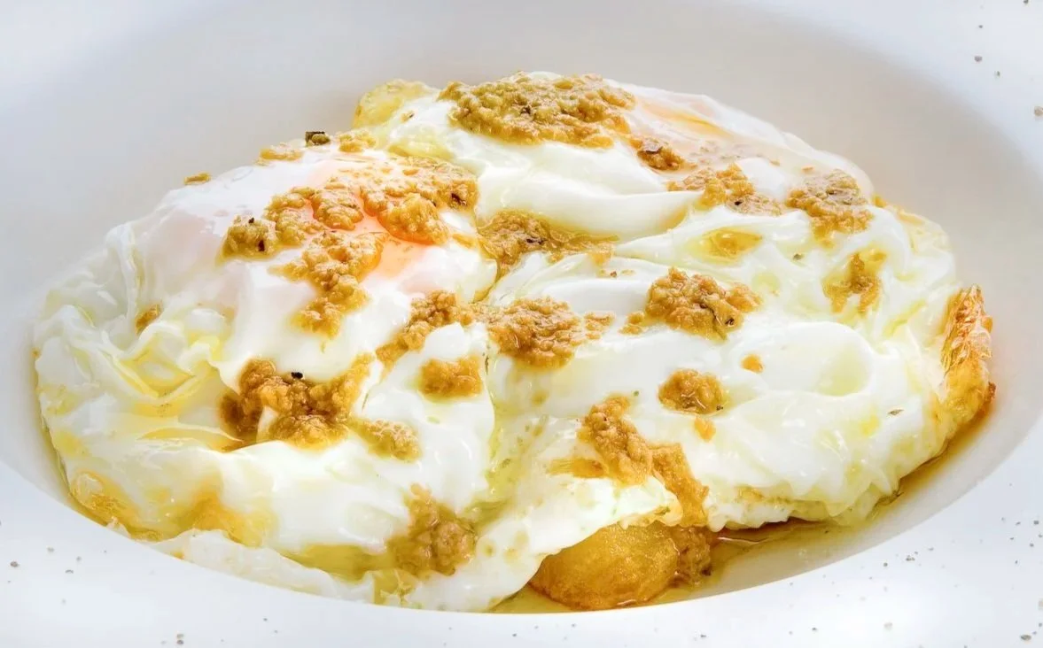 Detalle de huevos fritos con trufa en el restaurante del Hotel César (Vilanova i la Geltrú), fotografía gastronómica de textura e iluminación.