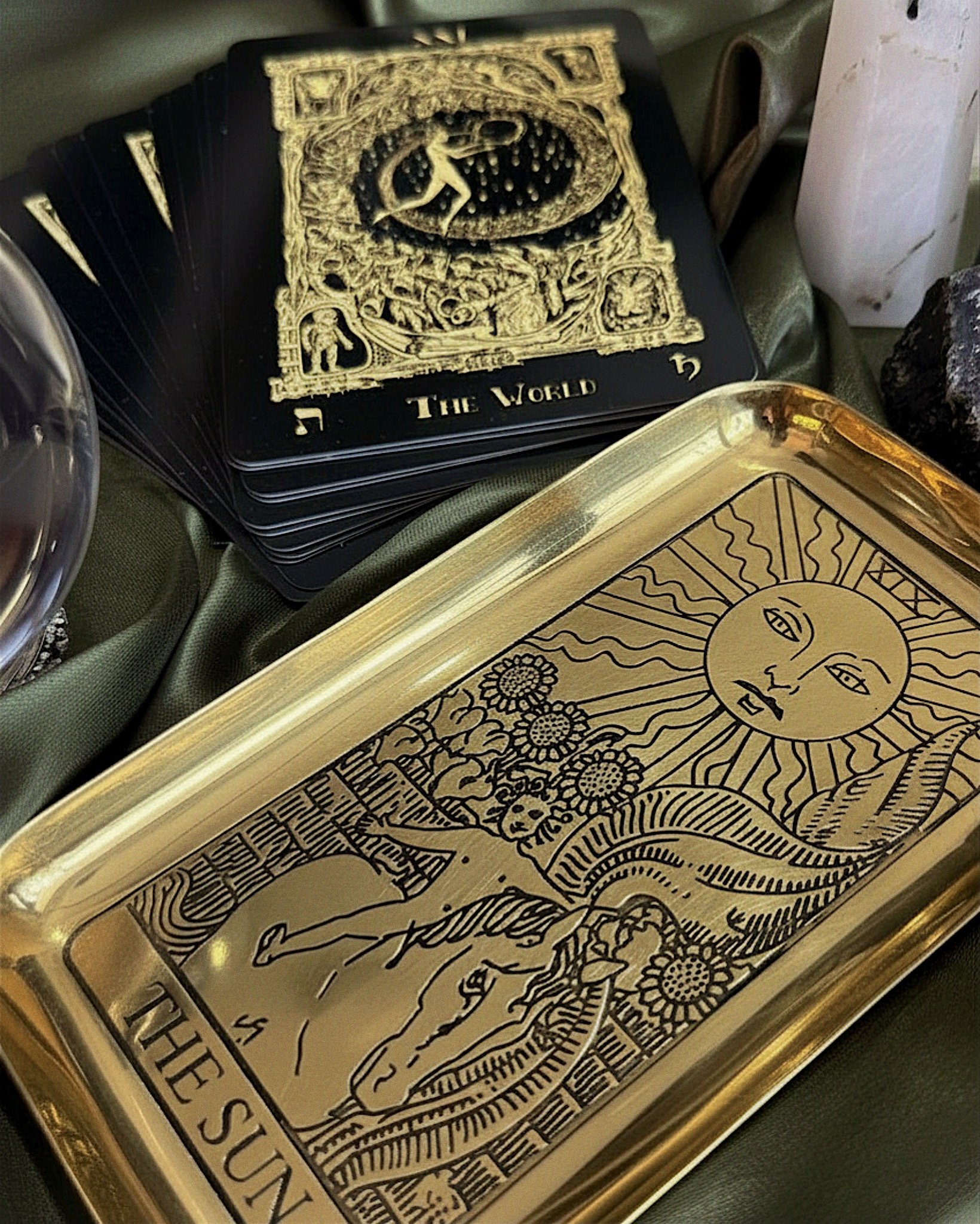 Gold tarot card tray with The Sun design styled beside tarot cards and crystal decor.