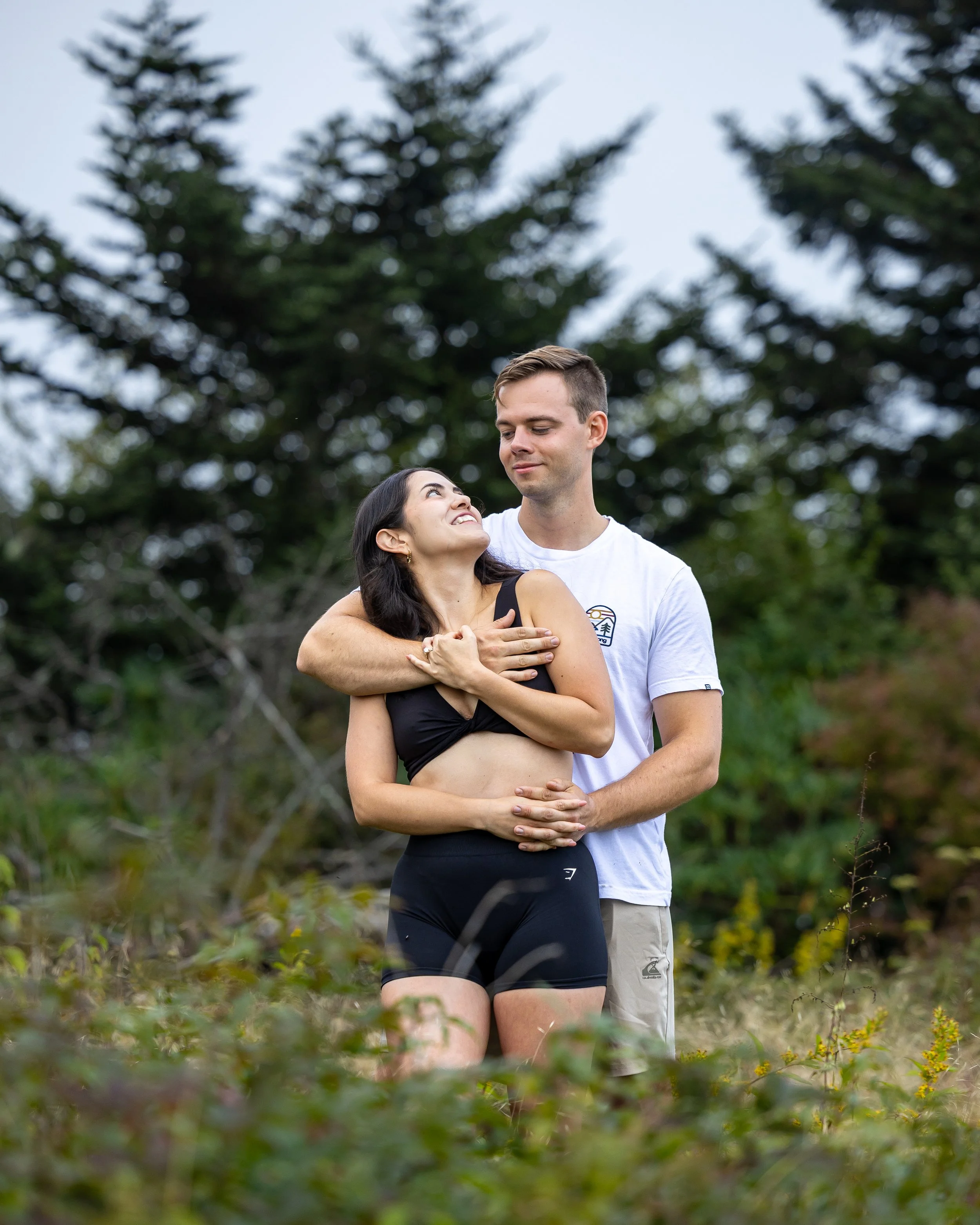 Newly engaged couple shares a quiet moment together surrounded by evergreens after a mountain proposal.