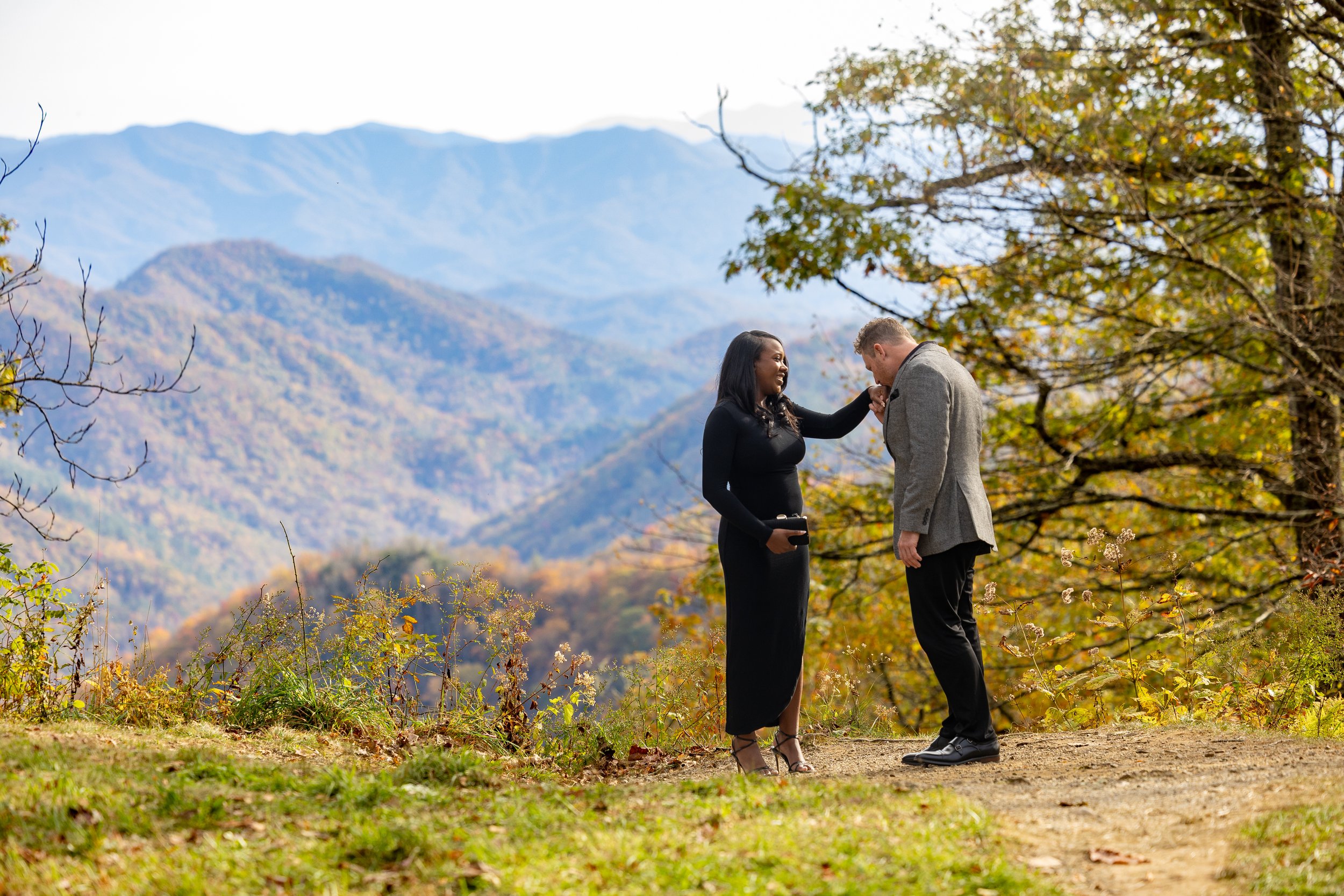 Man kisses his fiancée’s hand after a fall proposal overlooking the Great Smoky Mountains.
