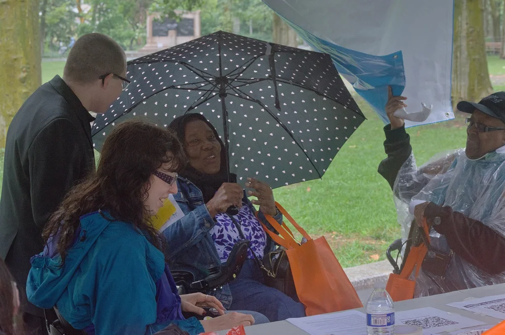  People gathered around one of the disability organization booths tabling for the event. 