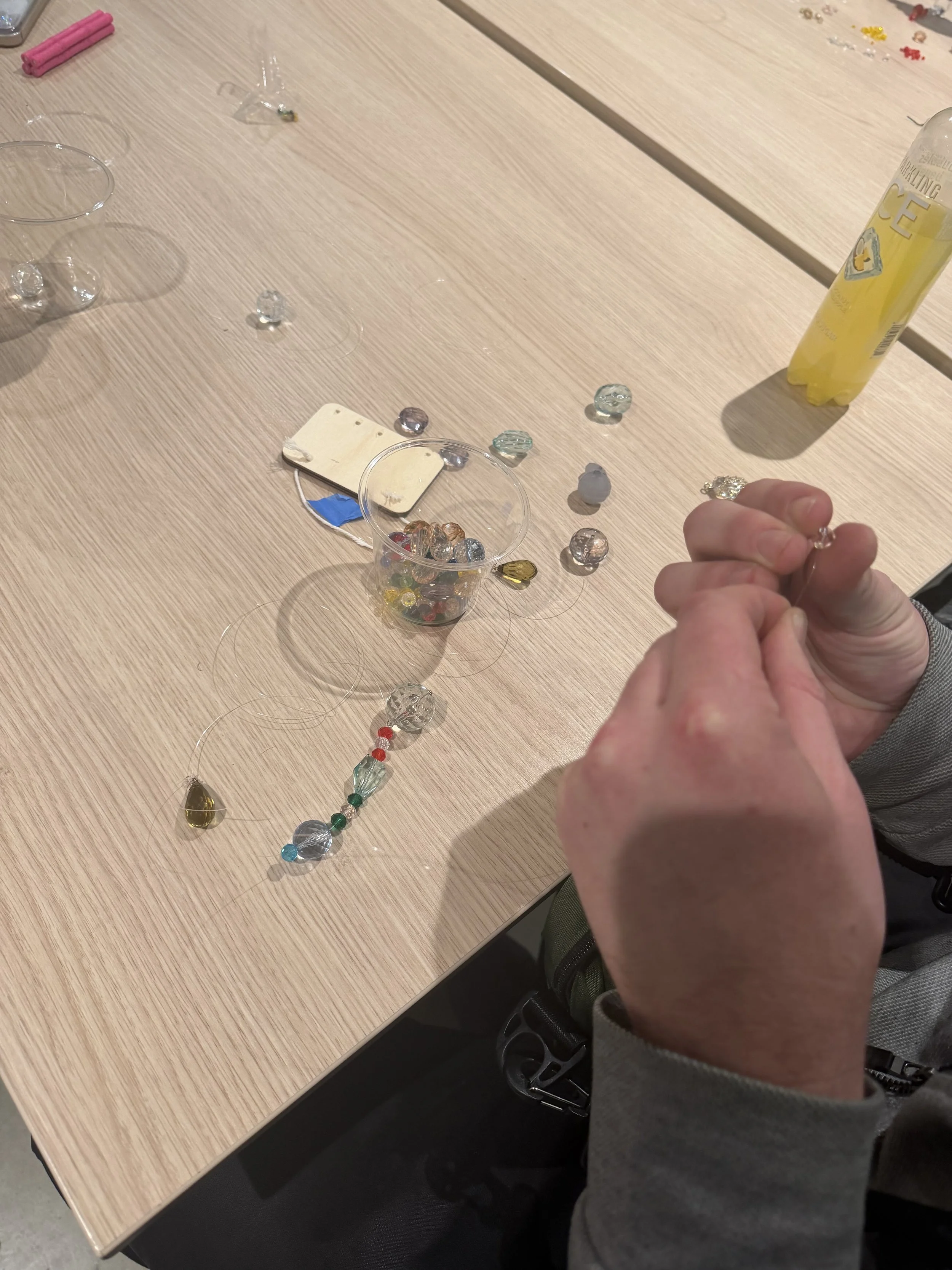  Close up of hands putting beads on a string. 