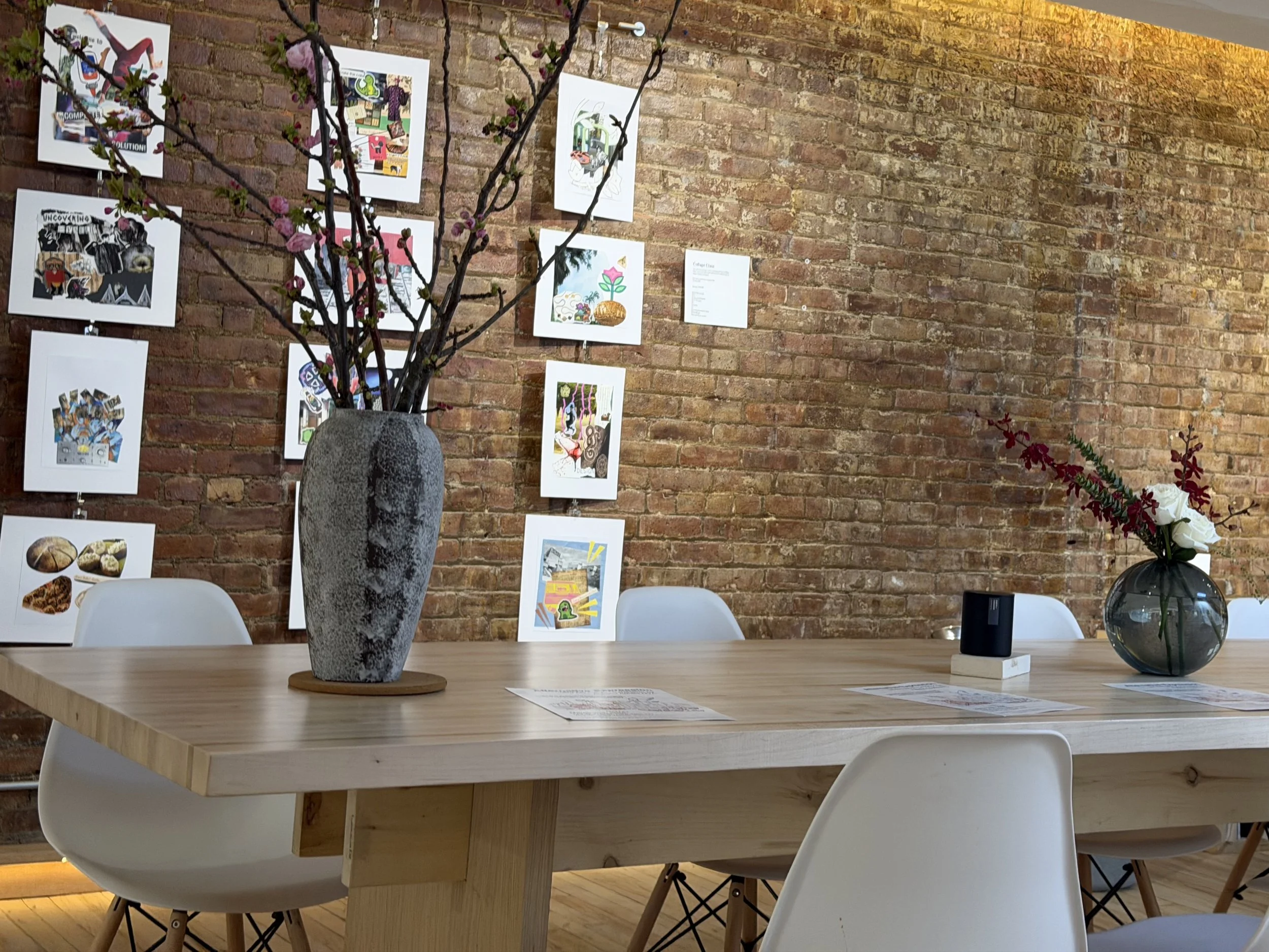  Image of floral arrangements on table, with artworks on the wall in the background.    