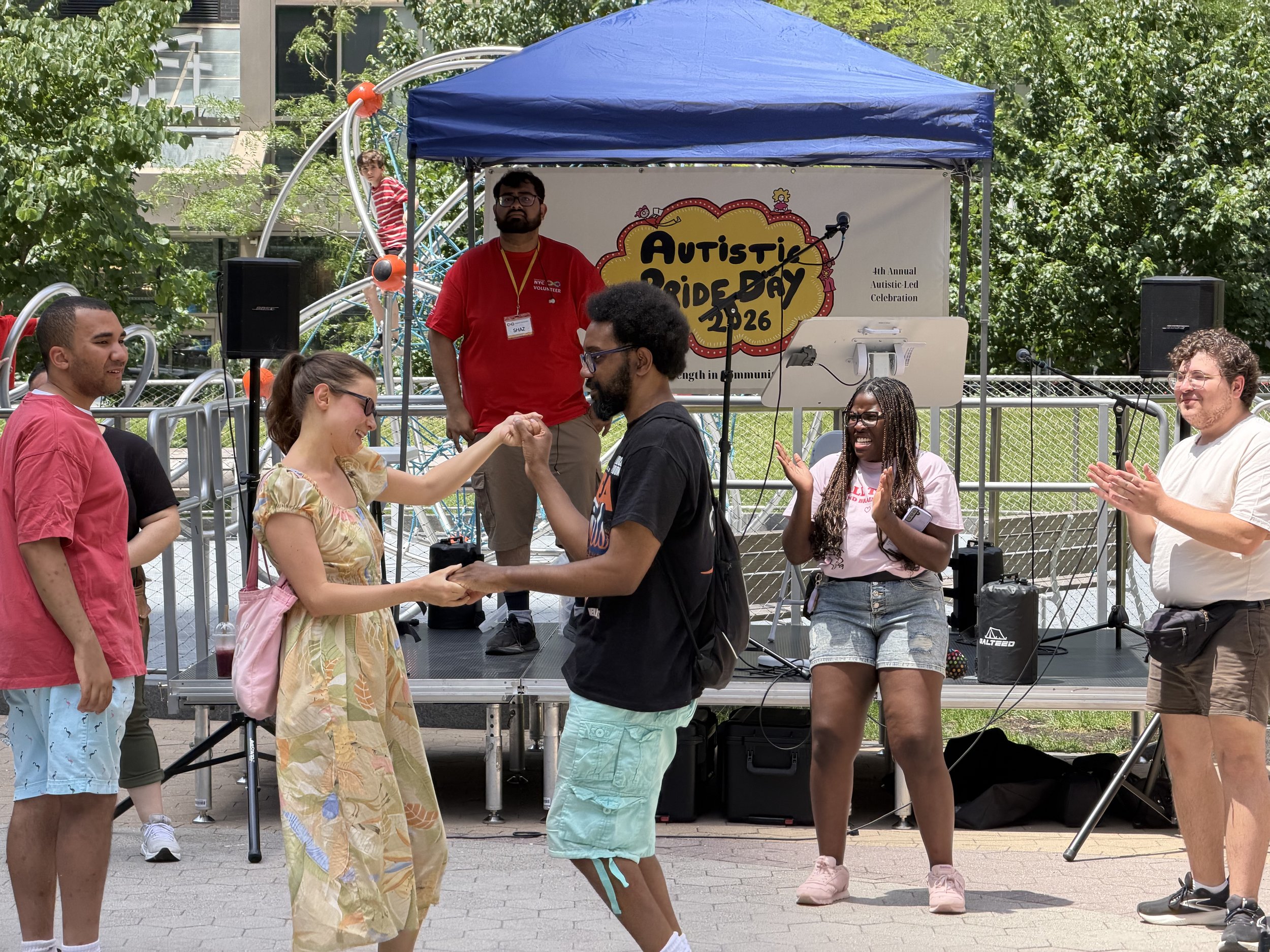  Two attendees holding hands and dancing, with others smiling and facing them 