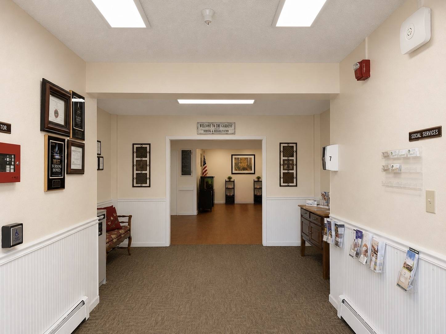 The Gardens Nursing & Rehabilitation entrance hallway with awards, brochures, and a welcome sign.
