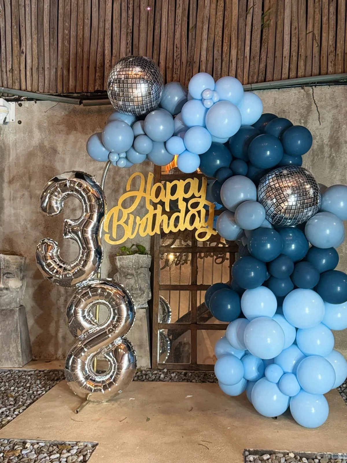 Balloon decoration for a birthday celebration with blue, black, and silver balloons, a 'Happy Birthday' sign, and large silver number balloons forming the number '32'.