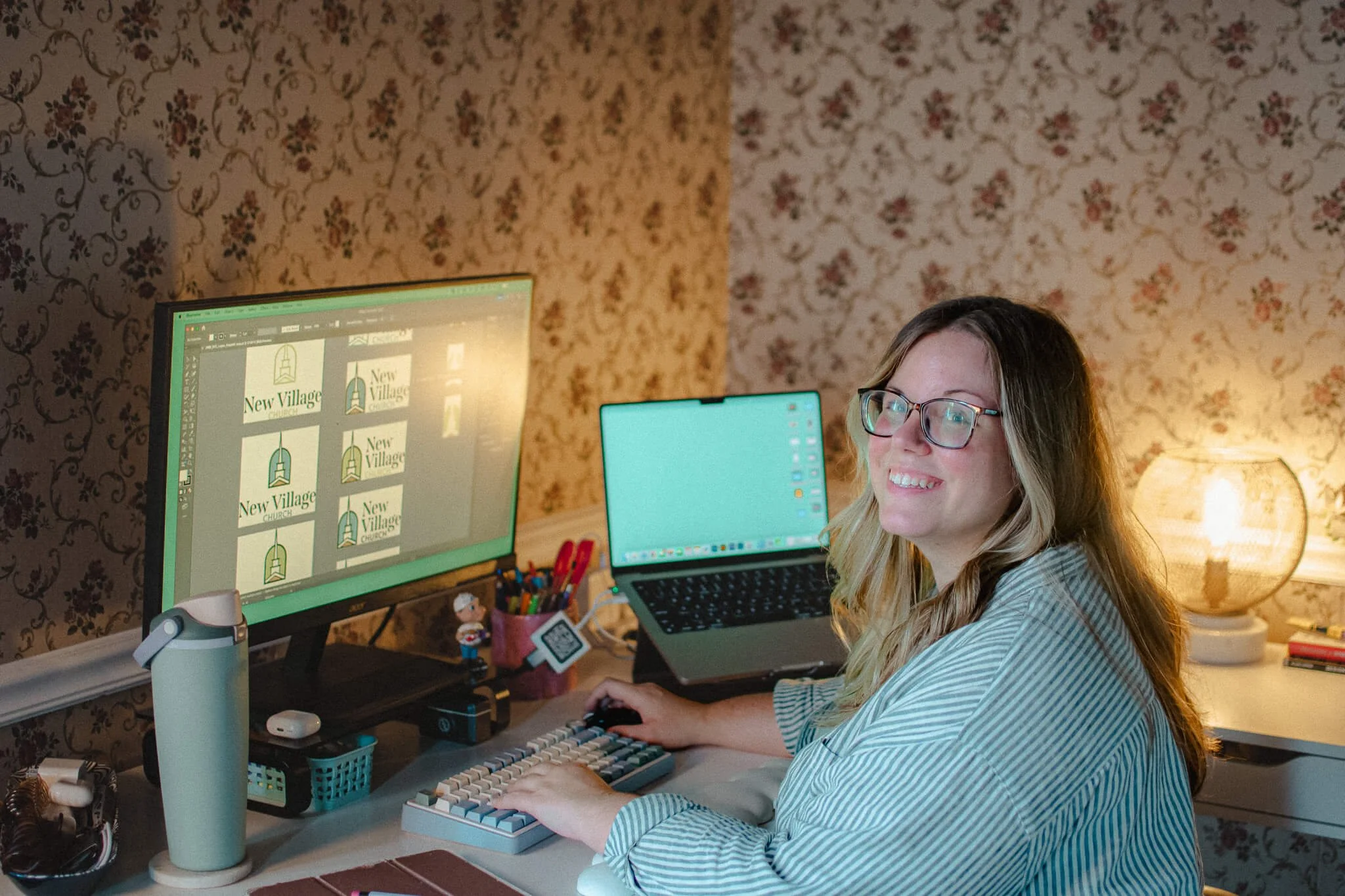 Paxton looking at the camera smiling while at her desk designing church logos branding