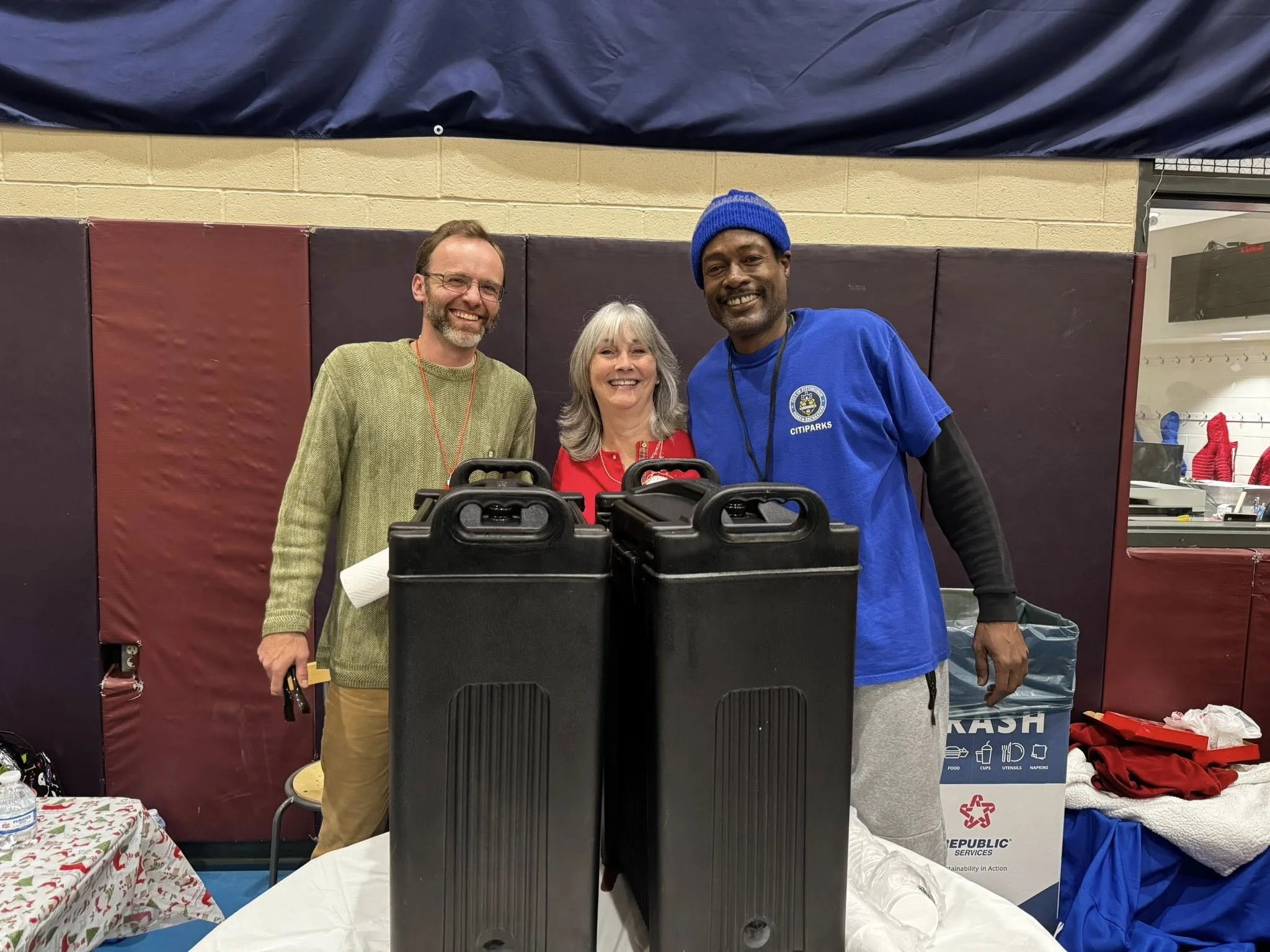 Three volunteers smiling behind a table at the Light Up Carrick event.