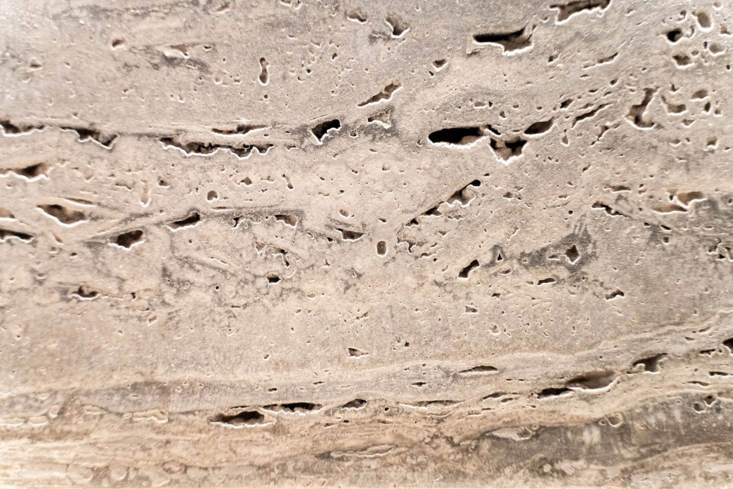 Close-up of a textured beige stone surface with natural holes and patterns.