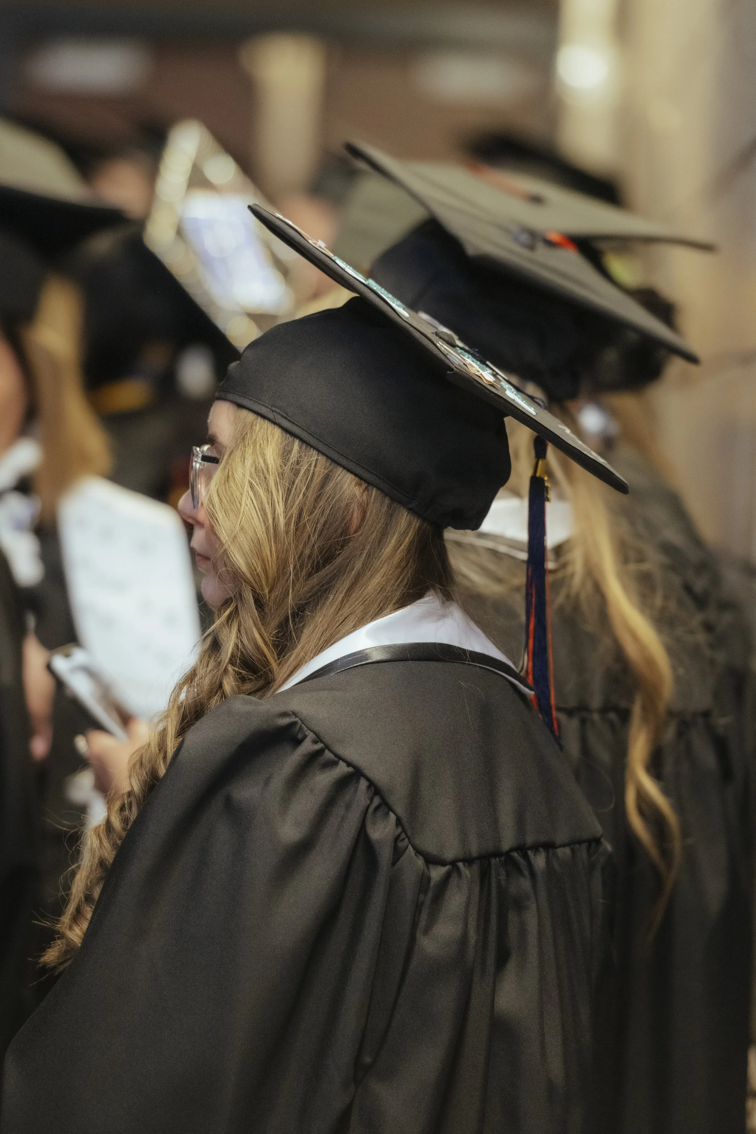 Female graduate wearing a black cap and gown during a graduation ceremony.
