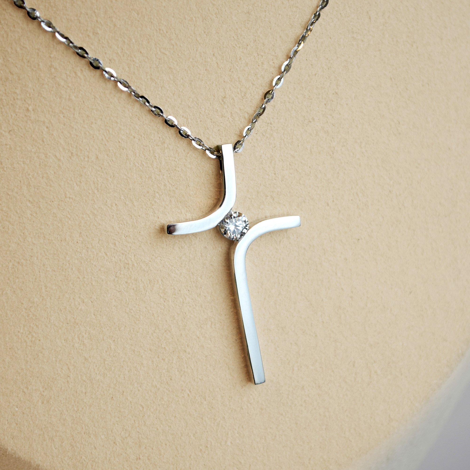 Elegant modern platinum cross necklace with a sparkling cremation diamond at the center.