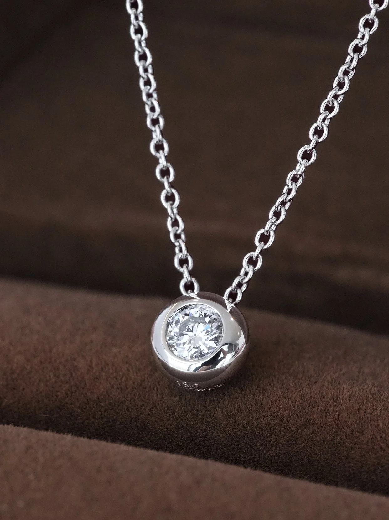  A sleek platinum bezel-set necklace featuring a brilliant round diamond, elegantly suspended on a delicate chain for timeless beauty.