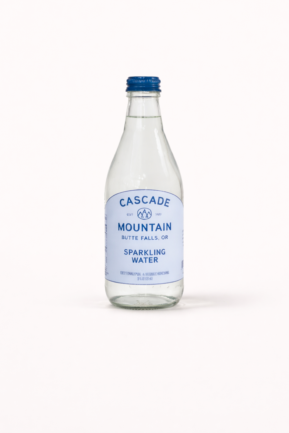 A clear glass bottle of Cascade Mountain sparkling water with a blue label and cap, standing on a plain white background.